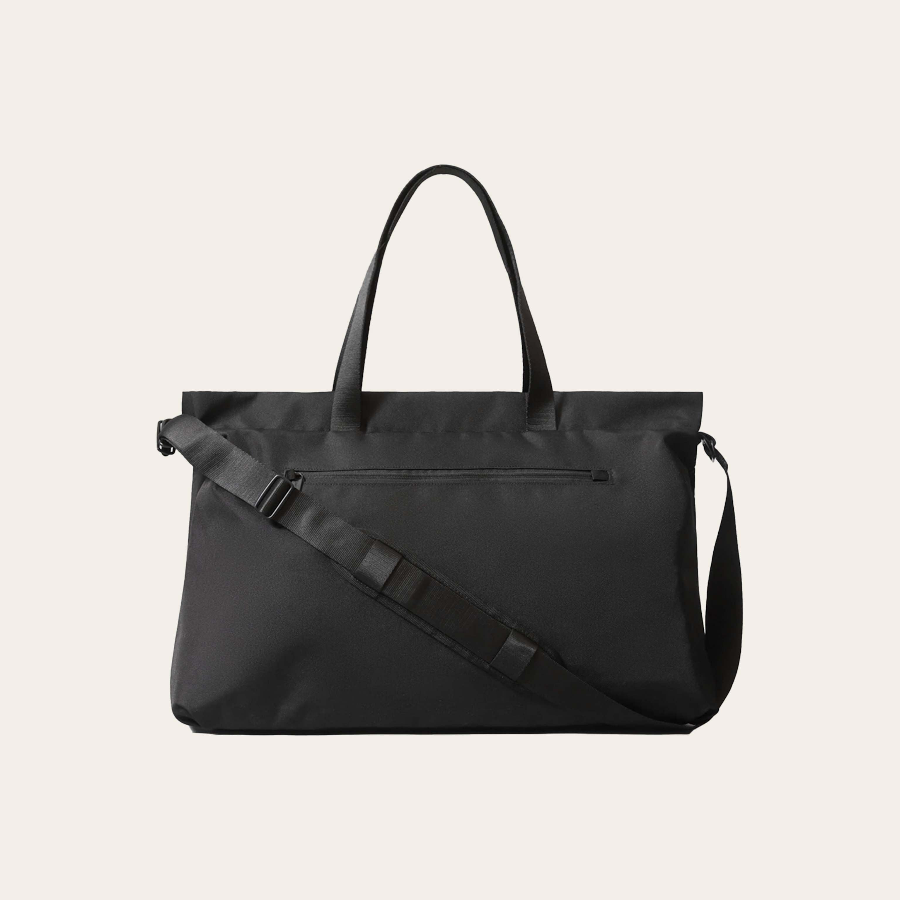 A black totebag with shoulder strap, against a tan background.
