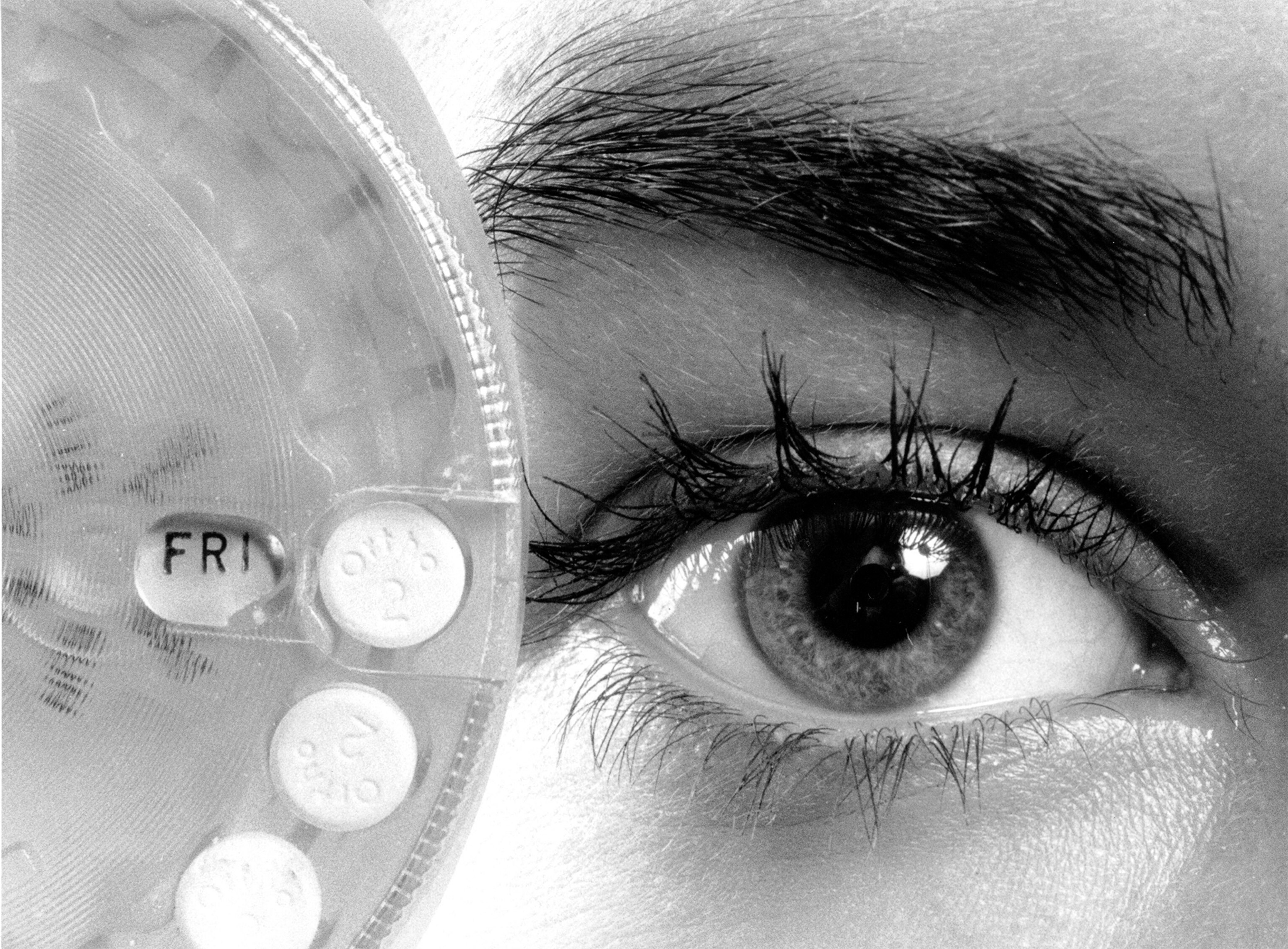 a woman holding a birth control dispenser close to her face in 1974.