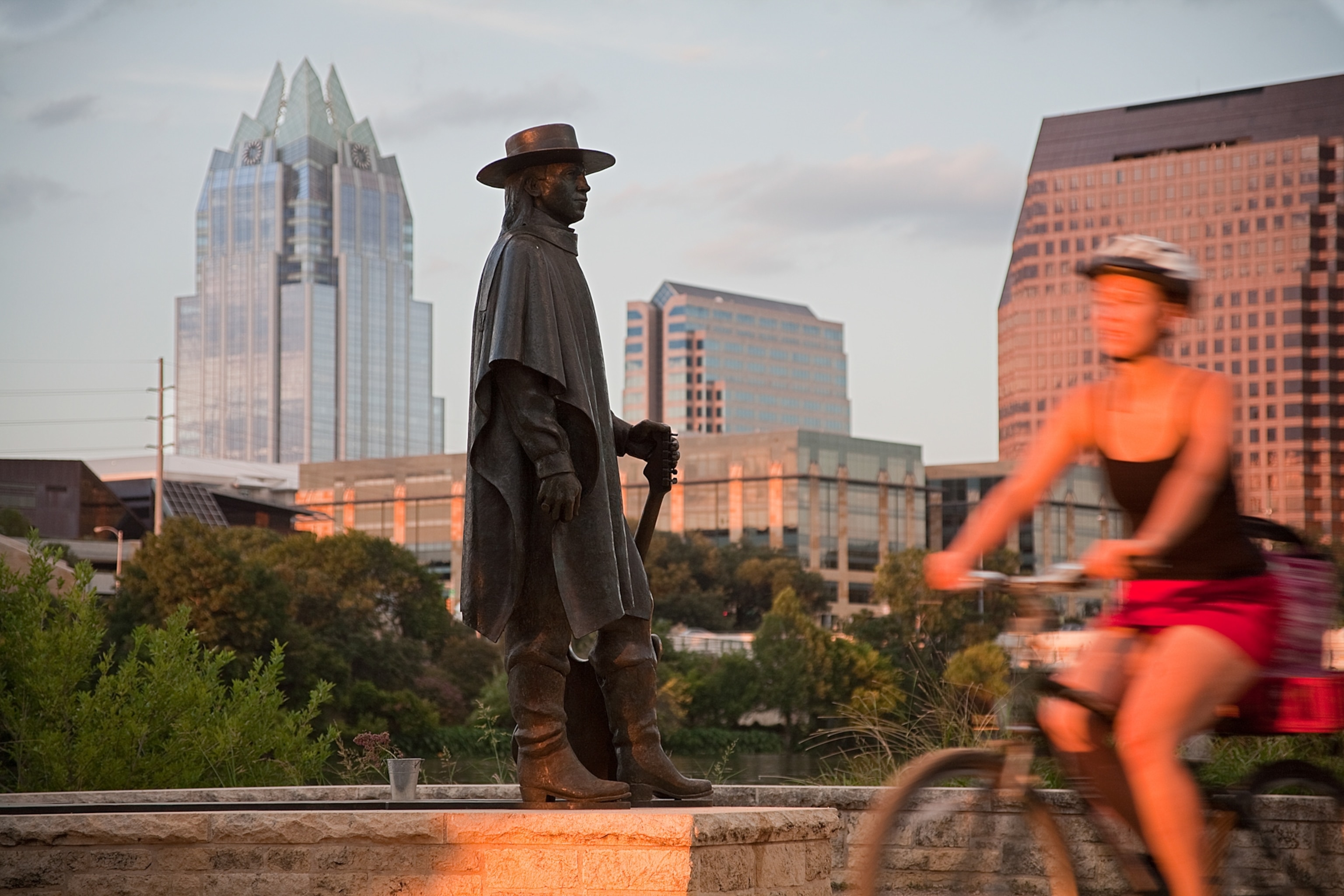 A statue of Stevie Ray Vaughn with the Austin skyline in the background.