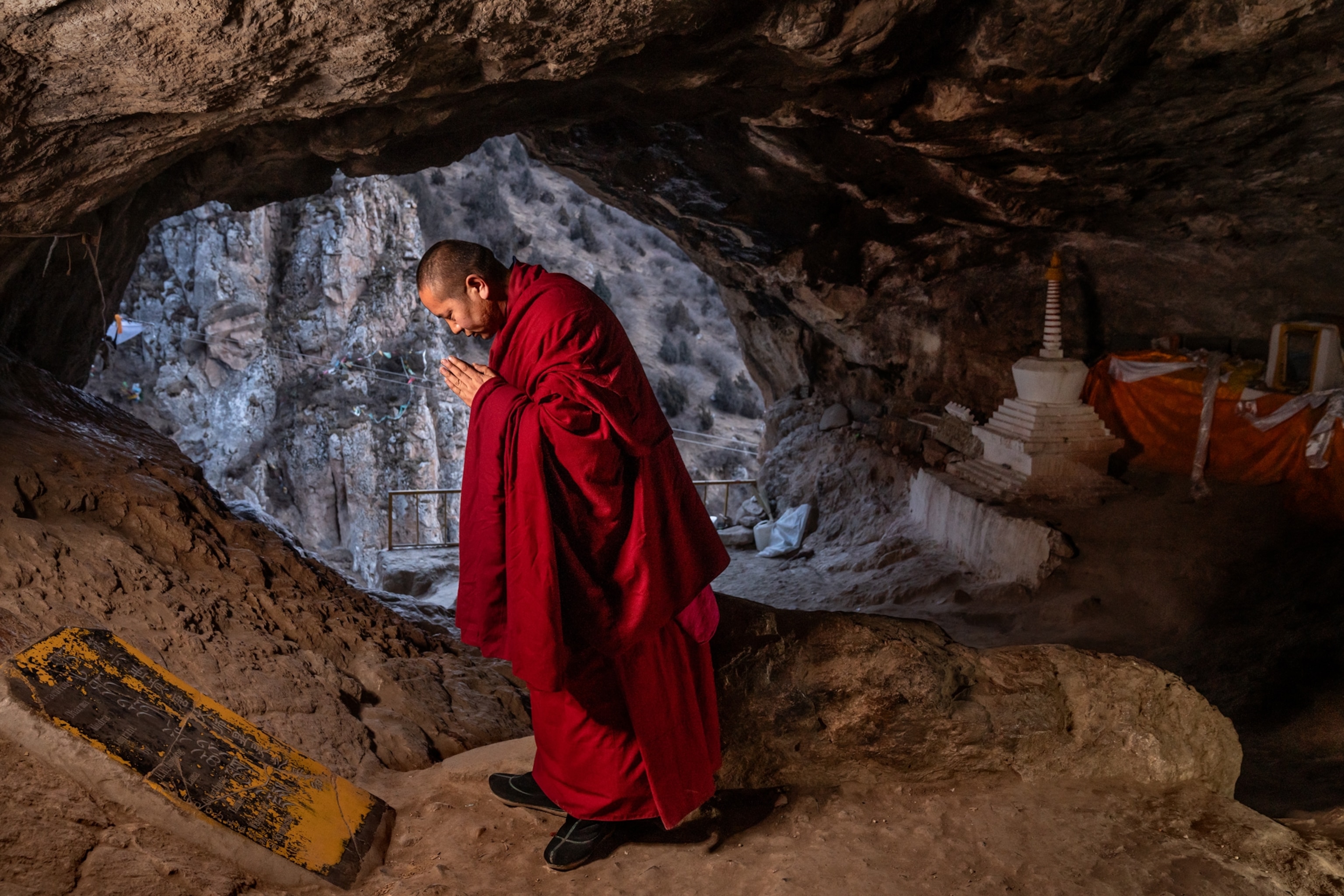 A monk prays inside of a cave.