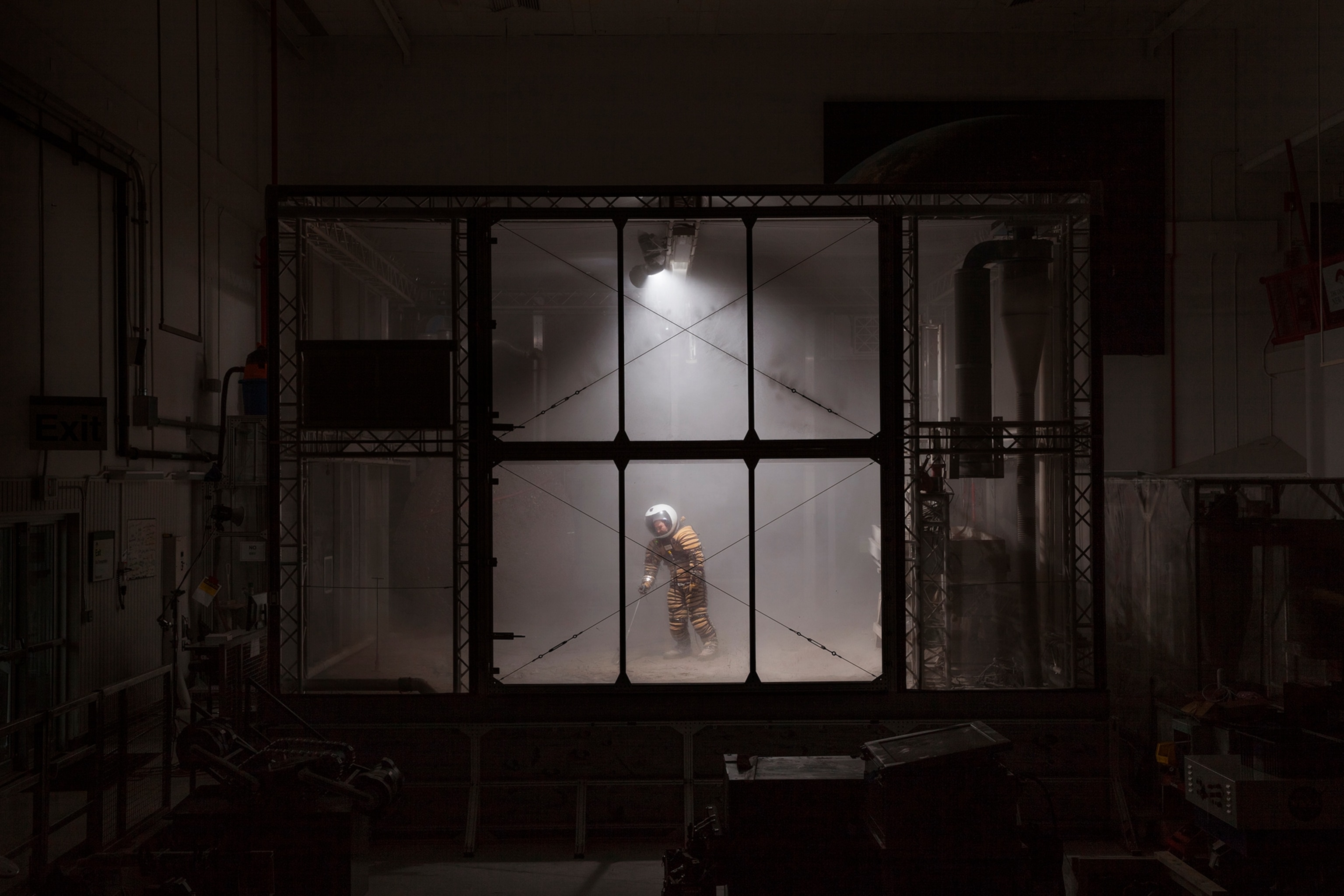 engineer testing a prototype space suit in simulated Mars dust storm inside the chamber