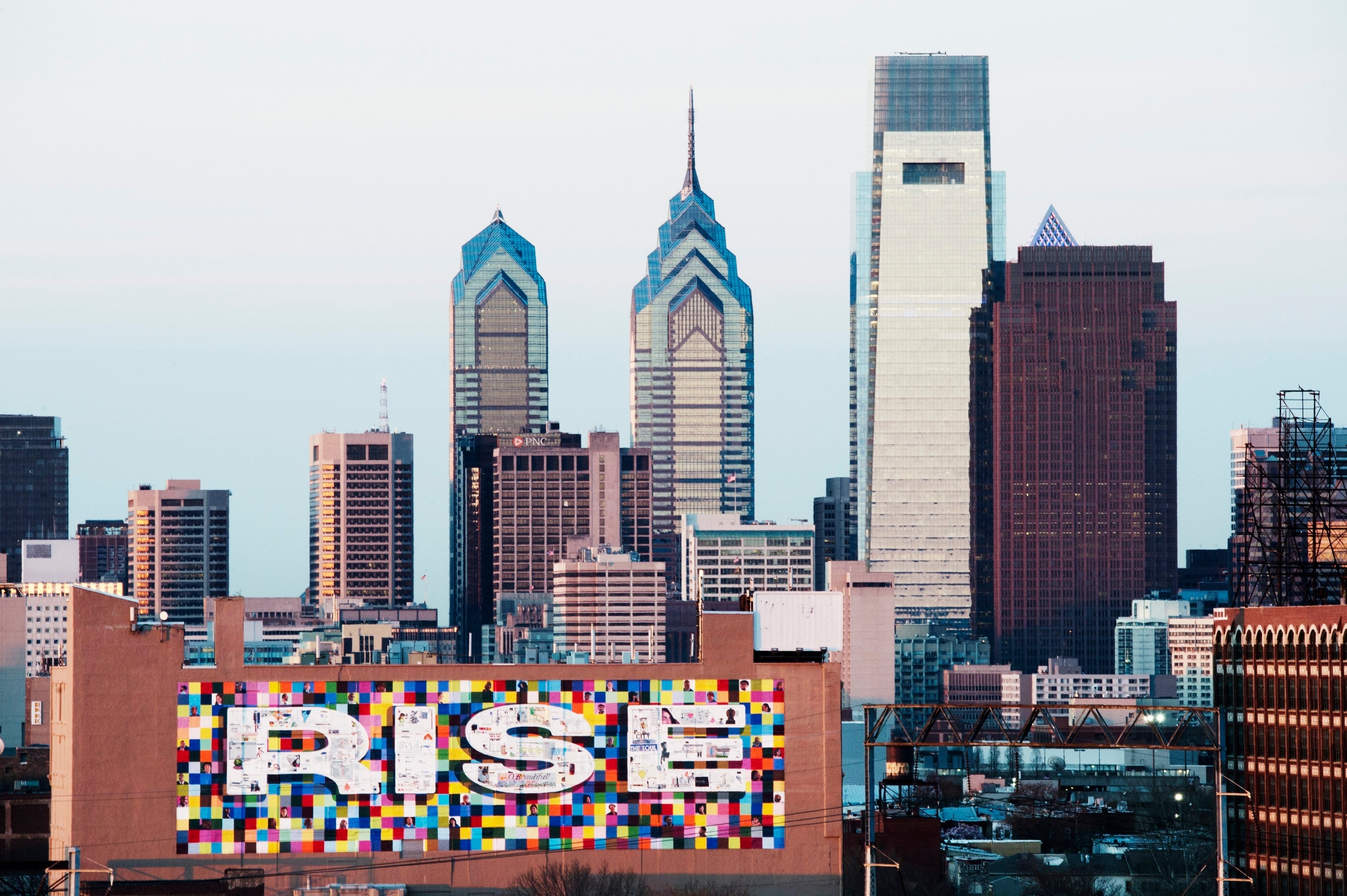 The Philadelphia skyline with a mural that says "RISE" in the foreground