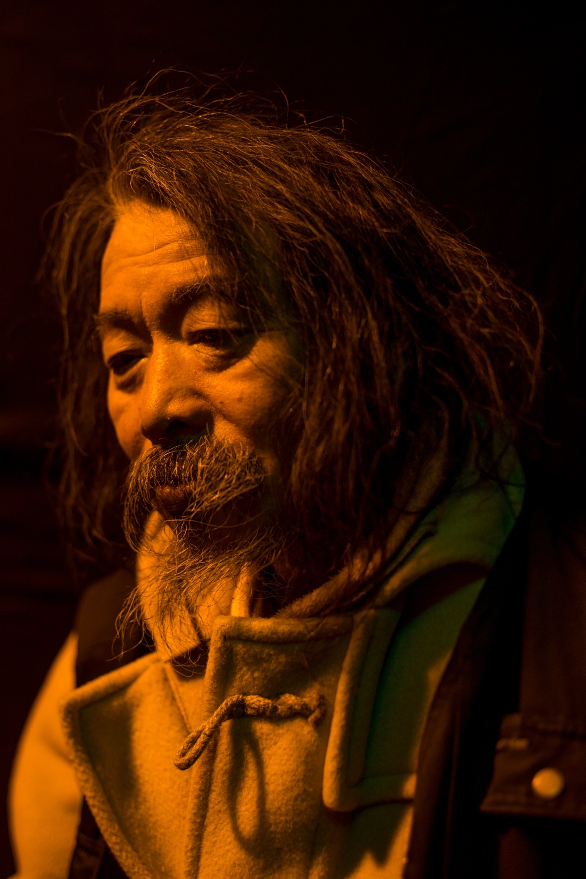 a man against a black background cast in neon orange light