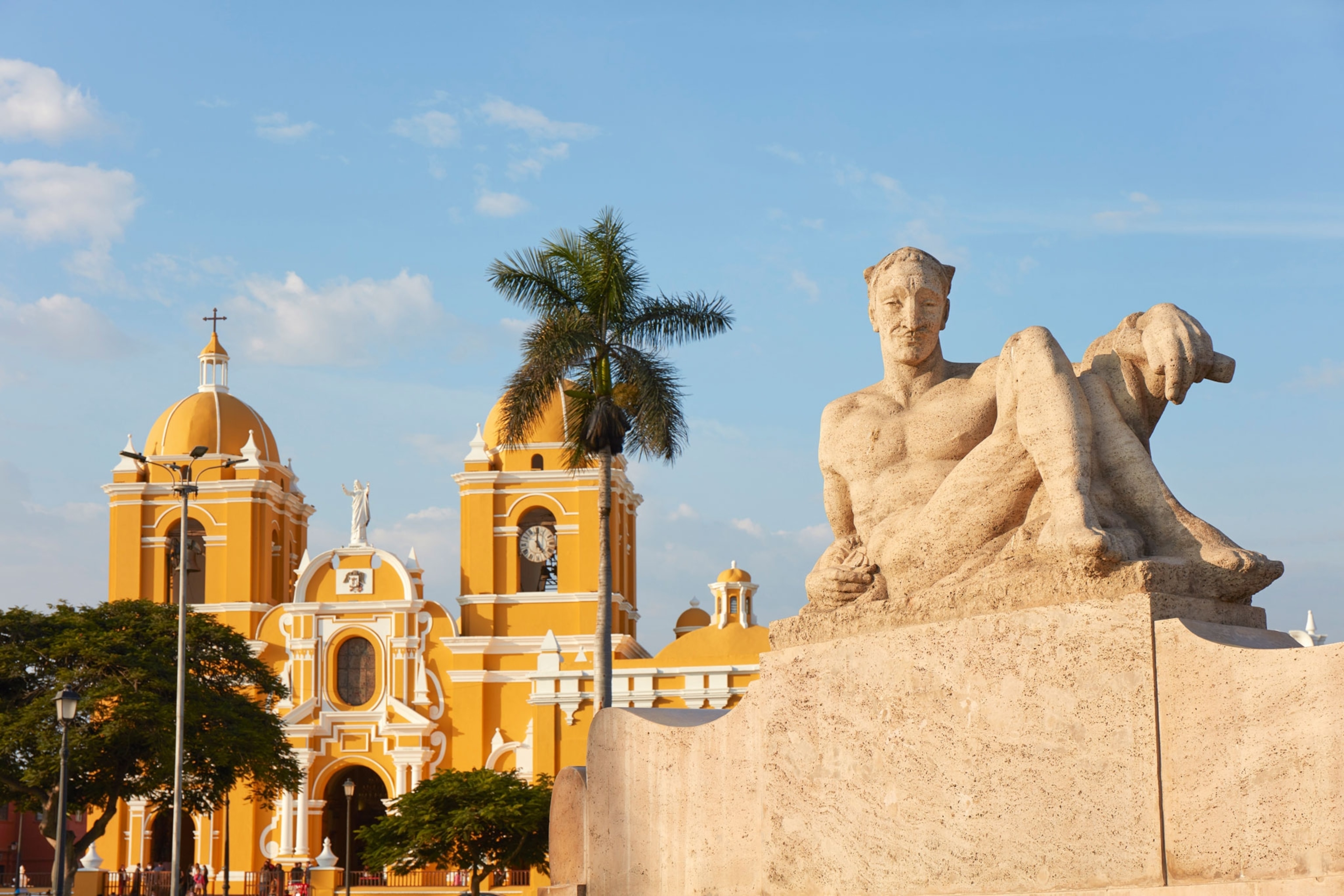 grand yellow building and statue with blue skies