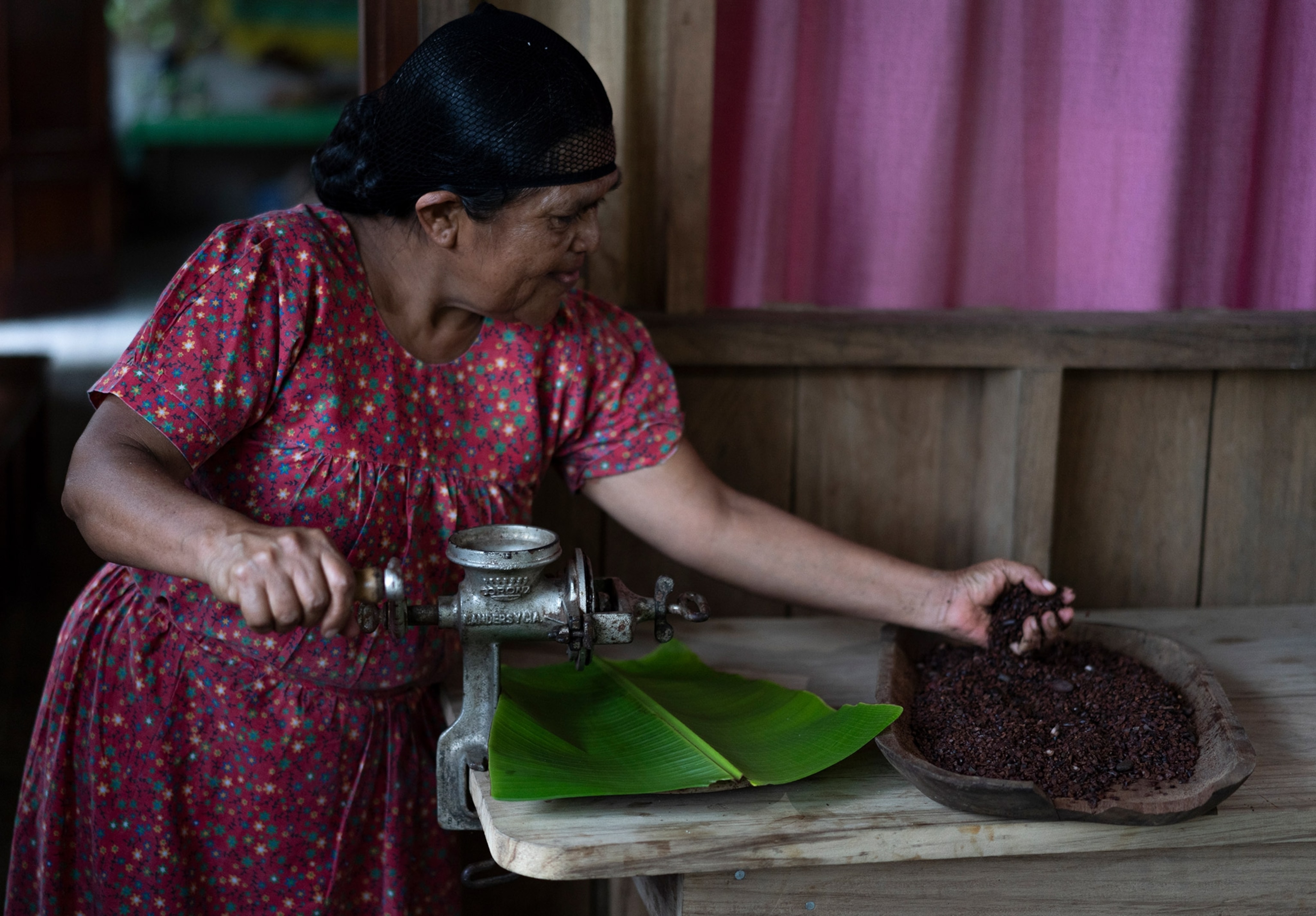A woman in a pink dress holds a cocoa in her hand with a soft smile.