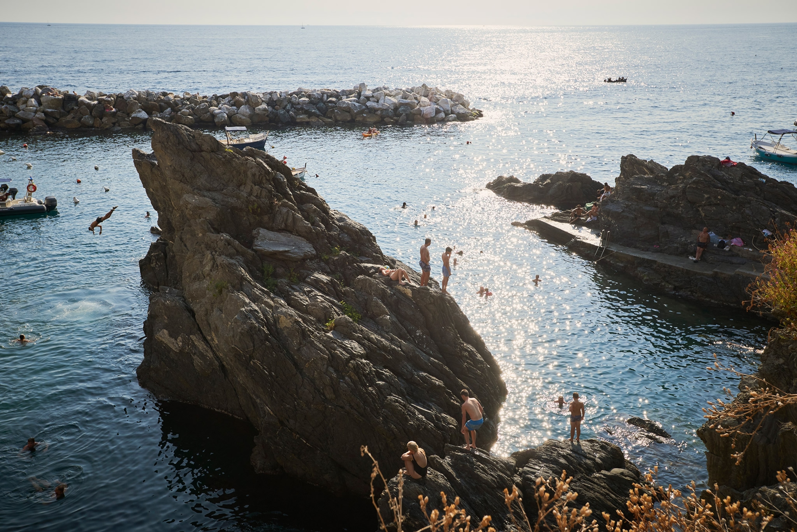 People swim and dive from the large rocks jutting from the ocean