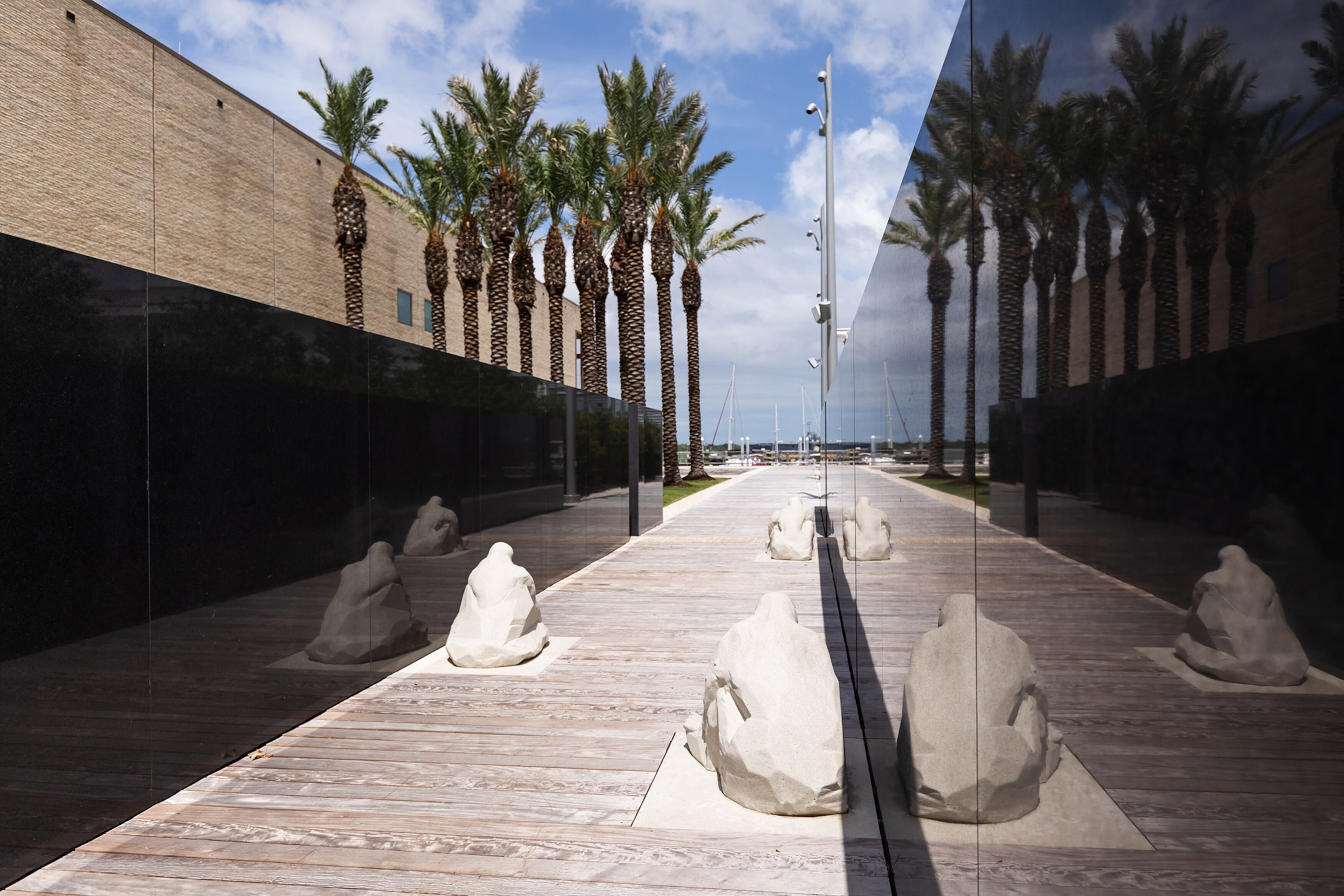 A sculpture instillation on the exterior of the museum facing the water with palm trees int he distance.