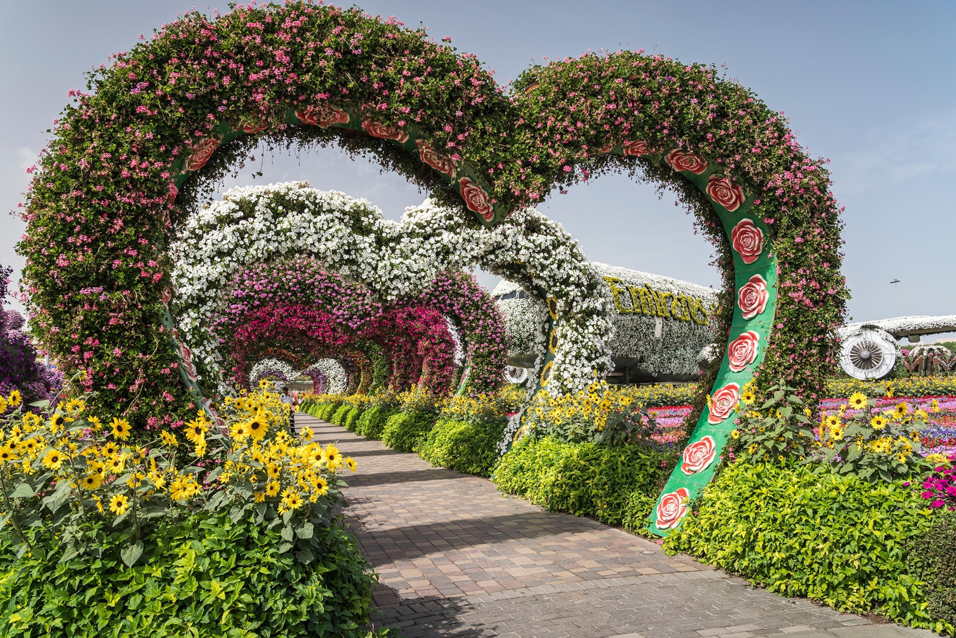 a heart shaped arrangement of flowers over a walkway in the Miracle Gardens in Dubai