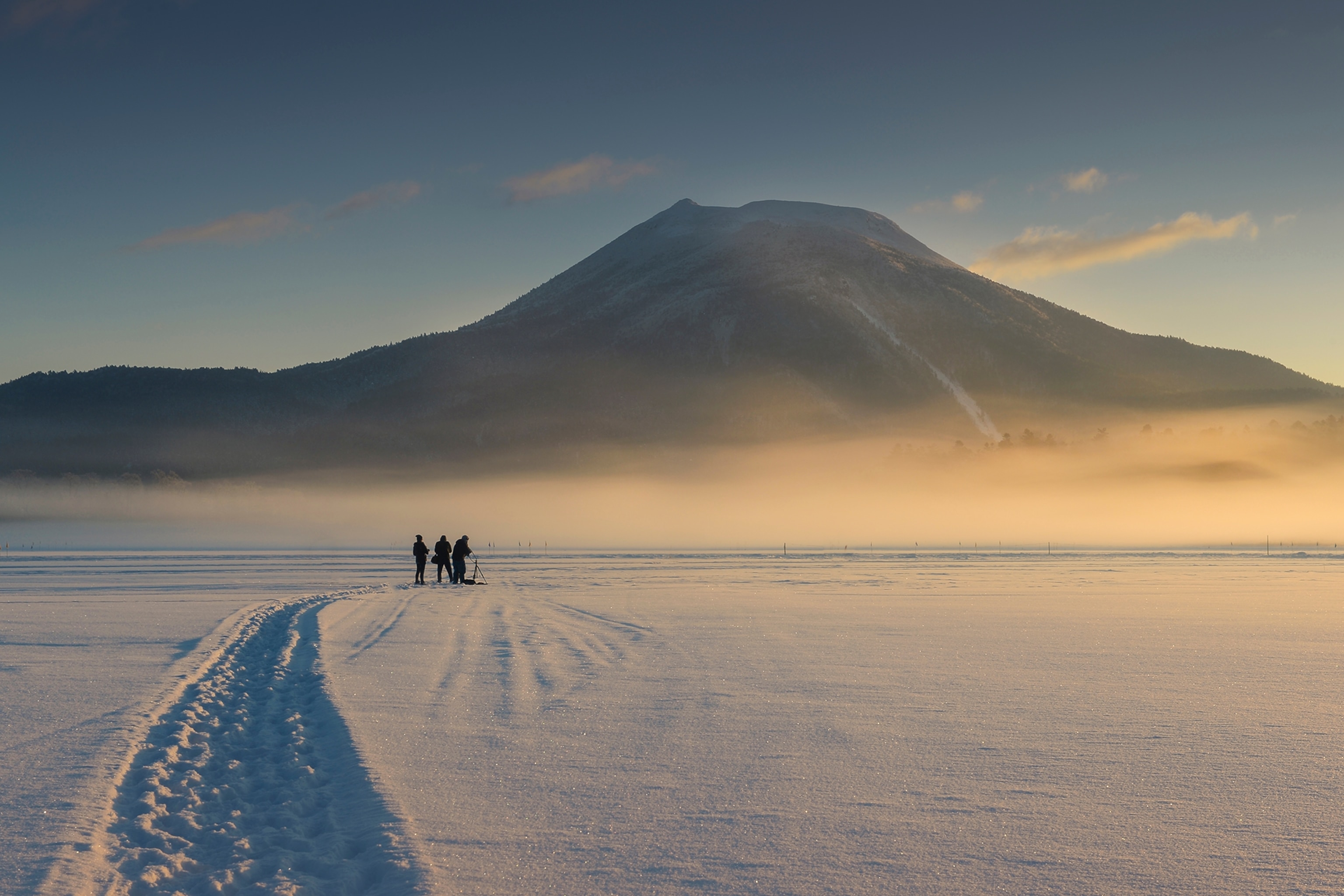 An epic panoramic view on a frozen and snowed in lake with Mount Fuji in the distance