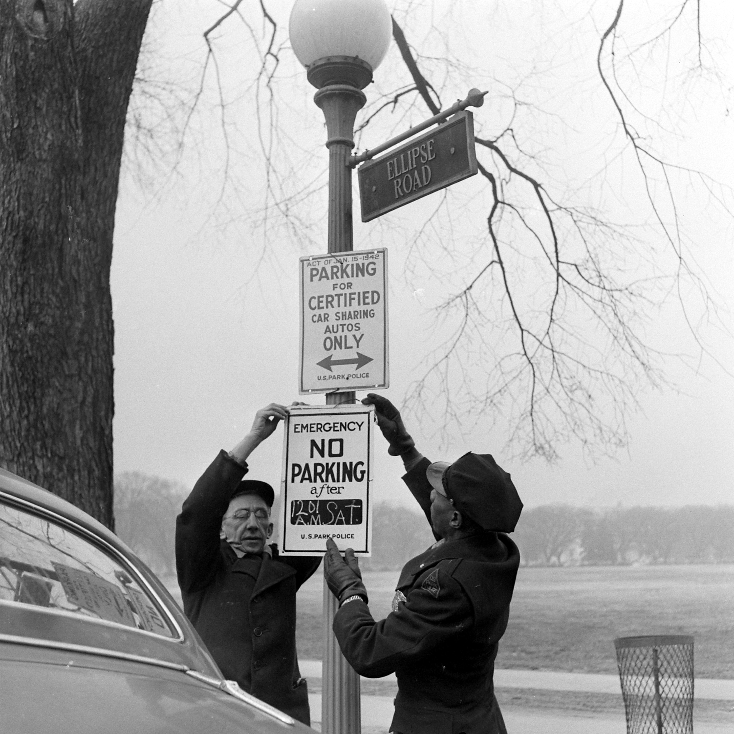 two people putting up a no parking sign in Washington D.C.