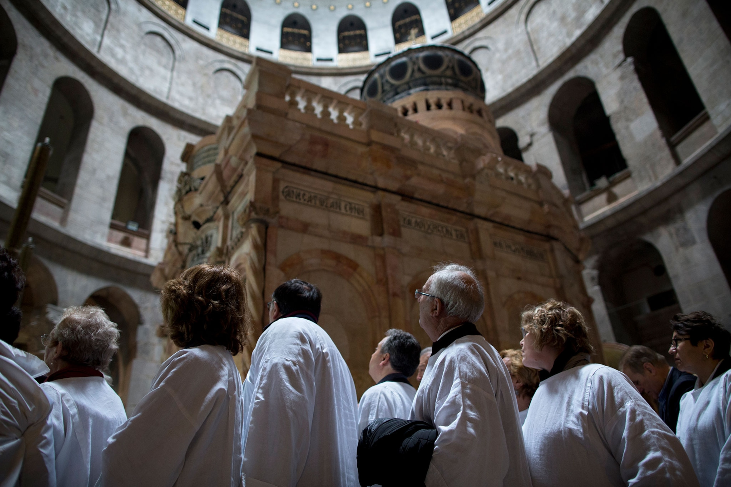 People stare at a structure inside a large church with archways.