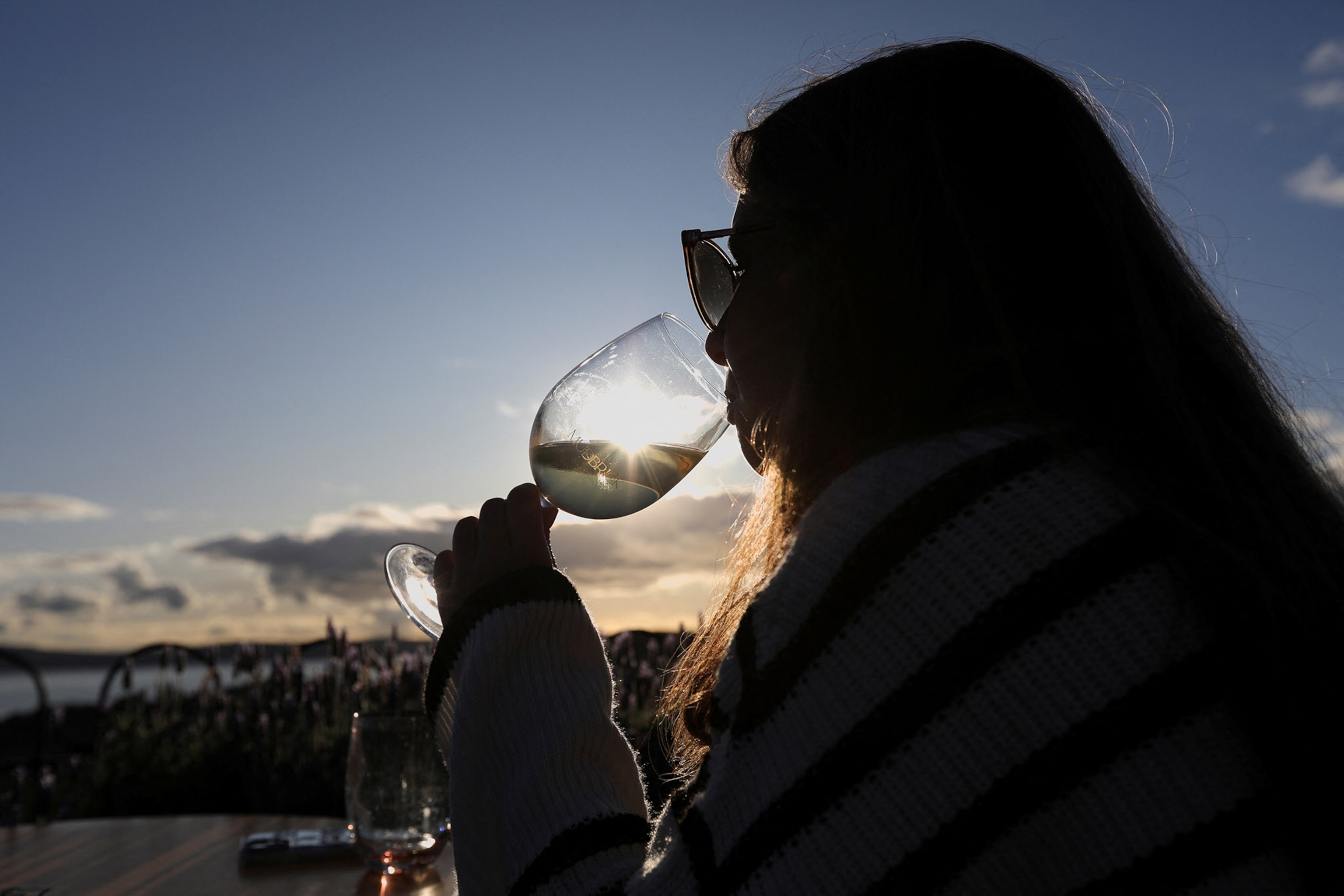 Rhiannon Howells, an England fan from Britain, sips a glass of wine at sunset at the Mudbrick Vineyard & Restaurant on Waiheke Island, New Zealand July 30, 2023.