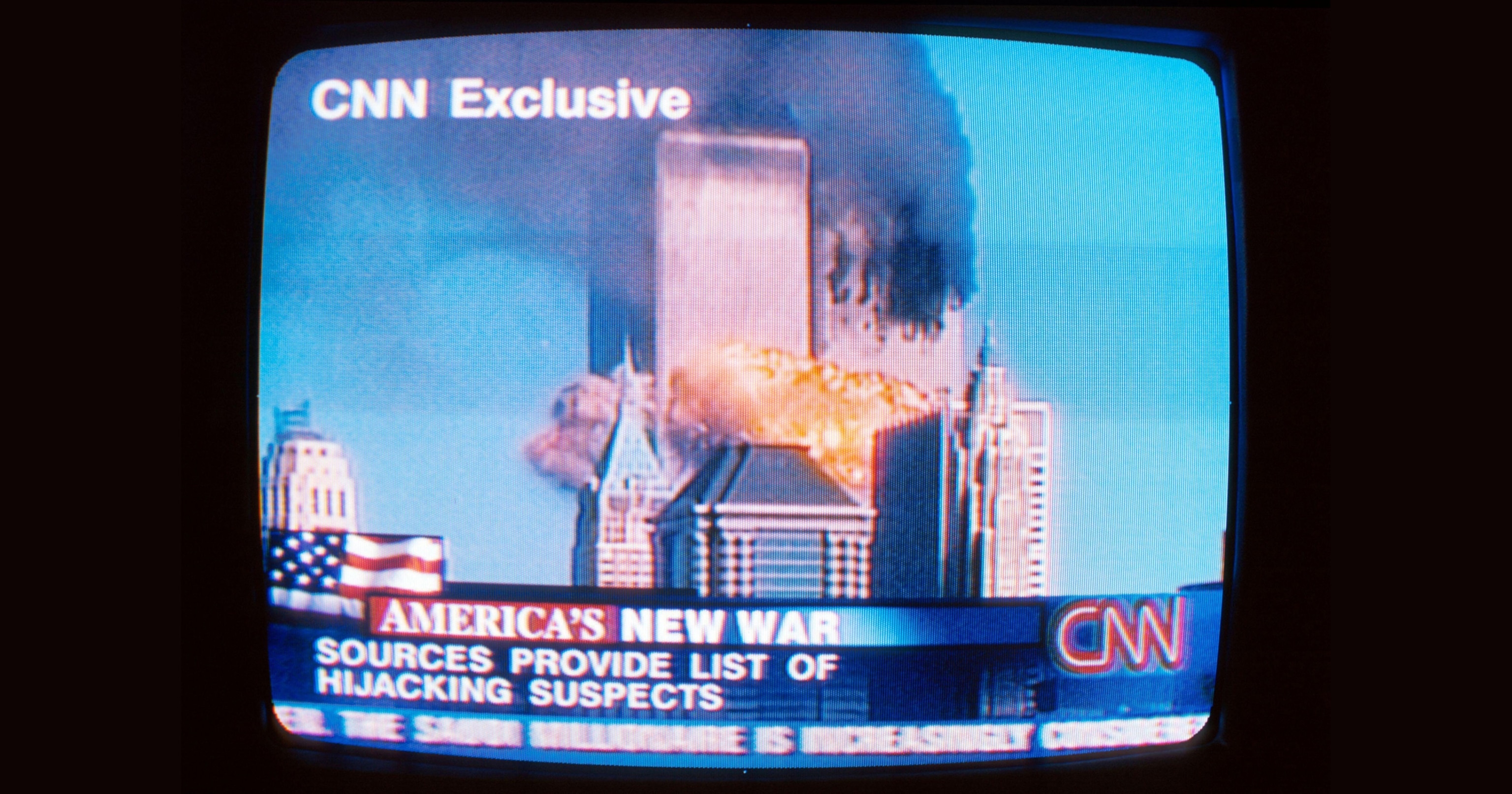 A television screen shows a CNN report of the twin towers/World Trade Center burning and collapsing.