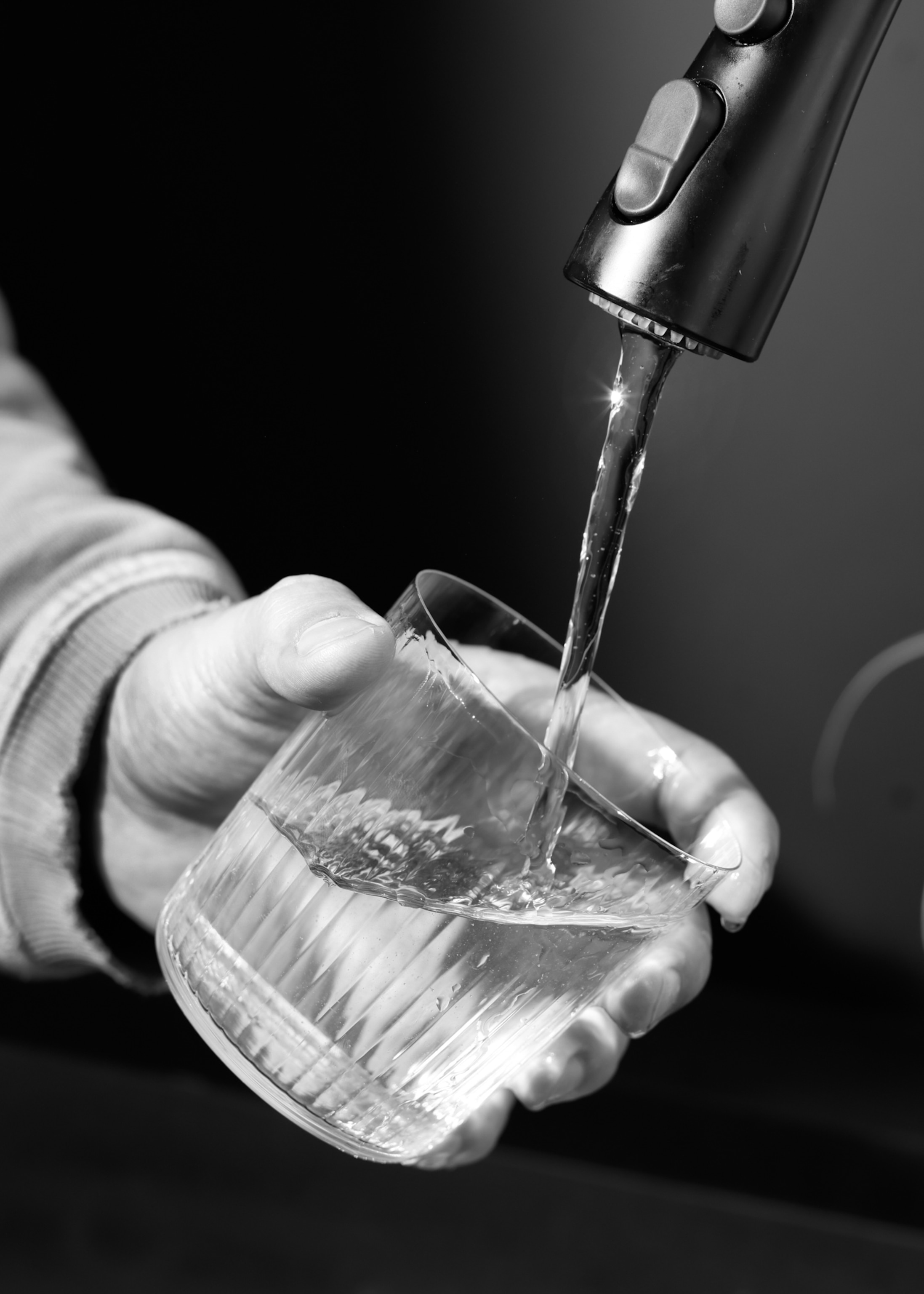 A close view of someone filling a glass with tap water.
