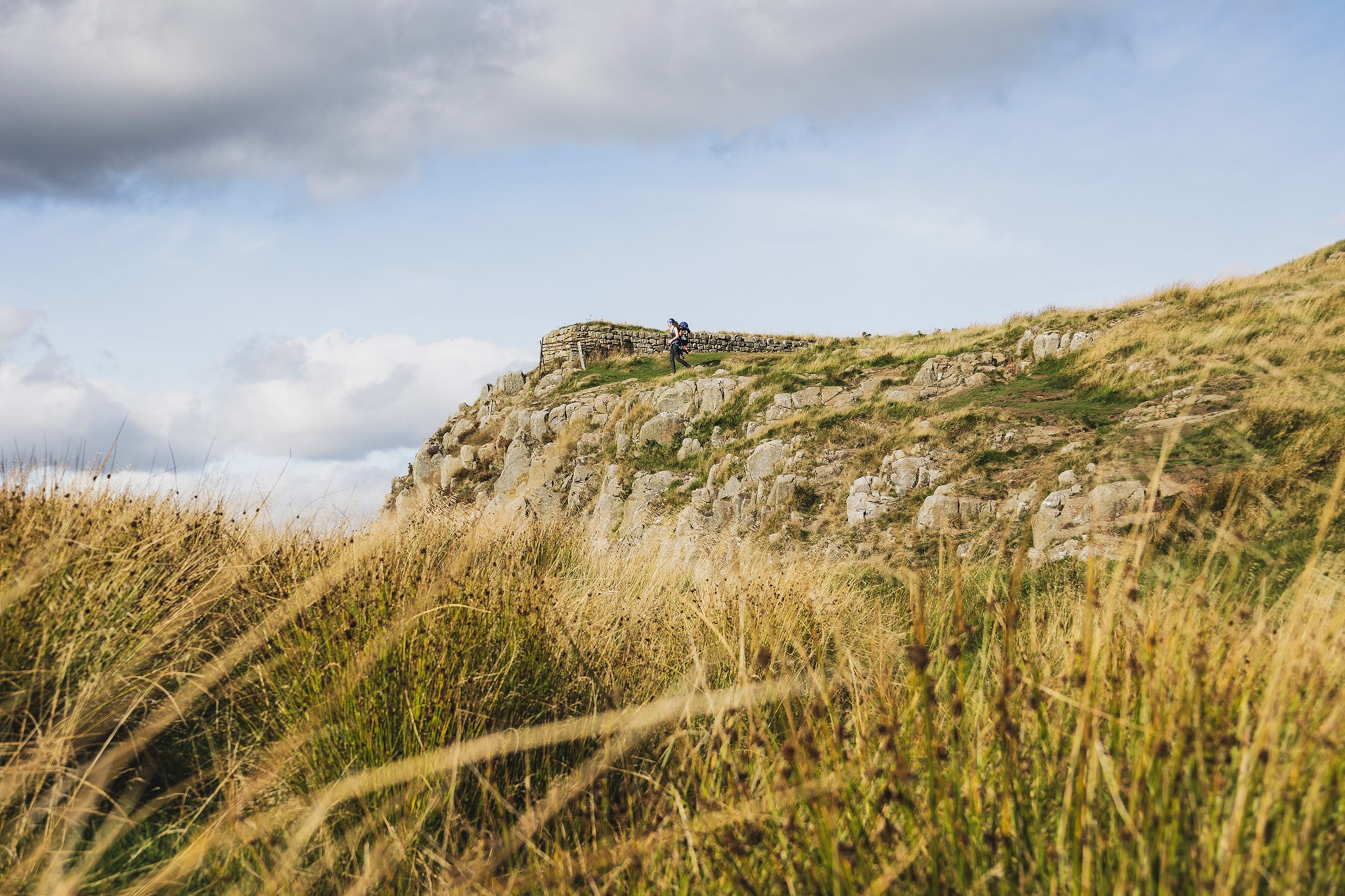 Grass blankets the foreground with a hiker in the distance
