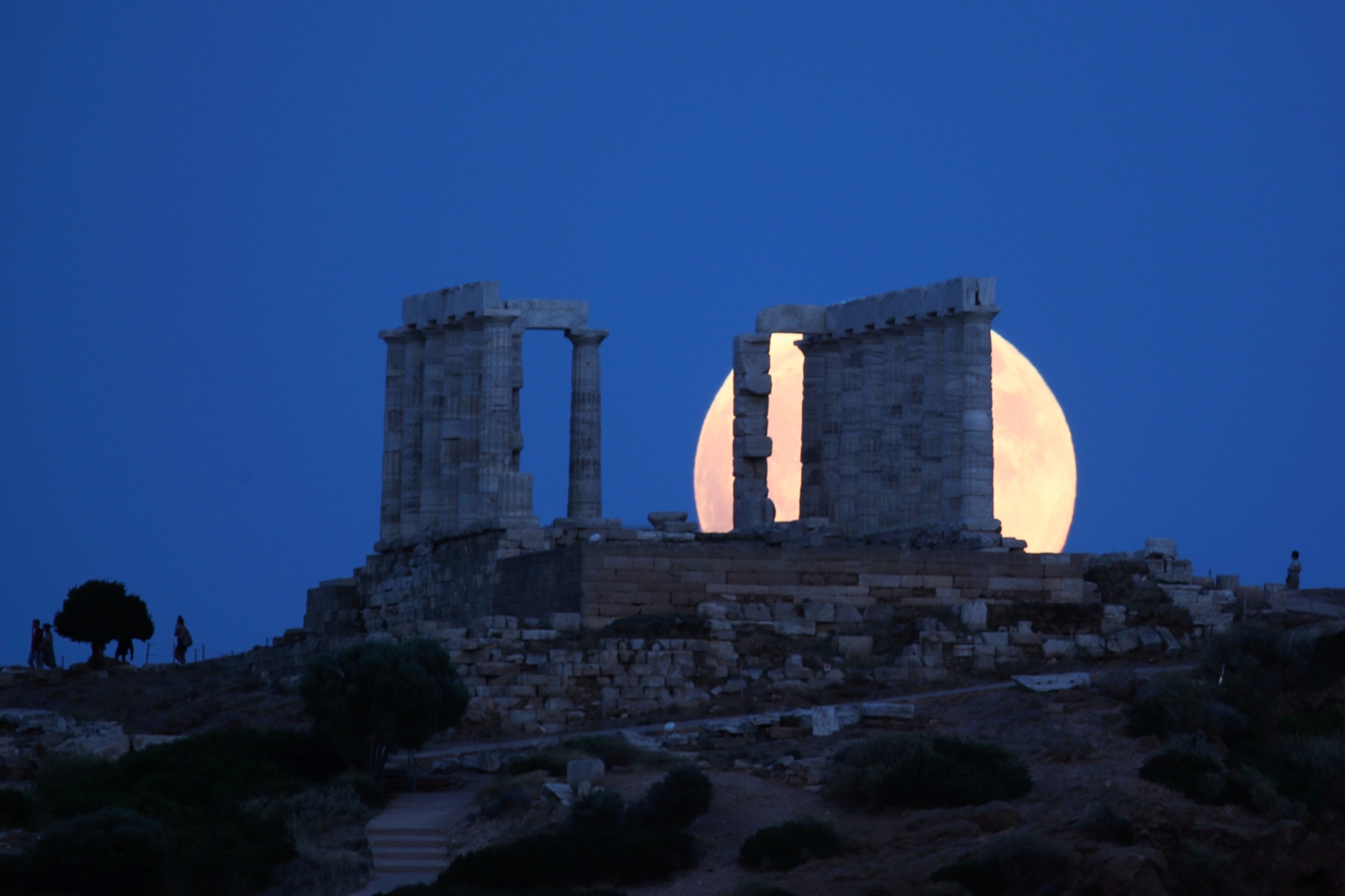 a full moon rising behind the ancient temple of Poseidon