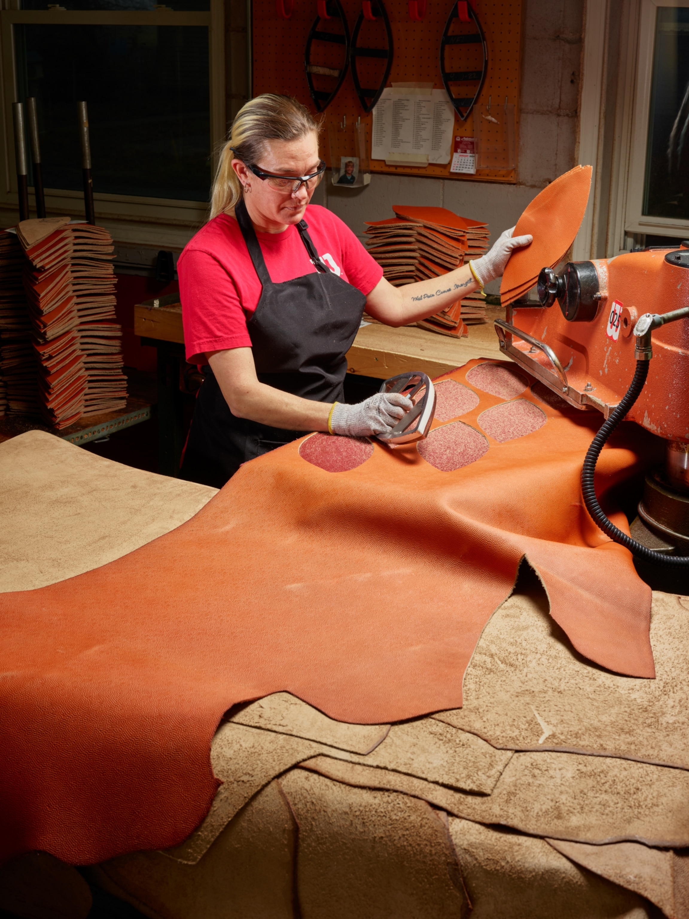 A factory worker cutting football panels out of leather hide.