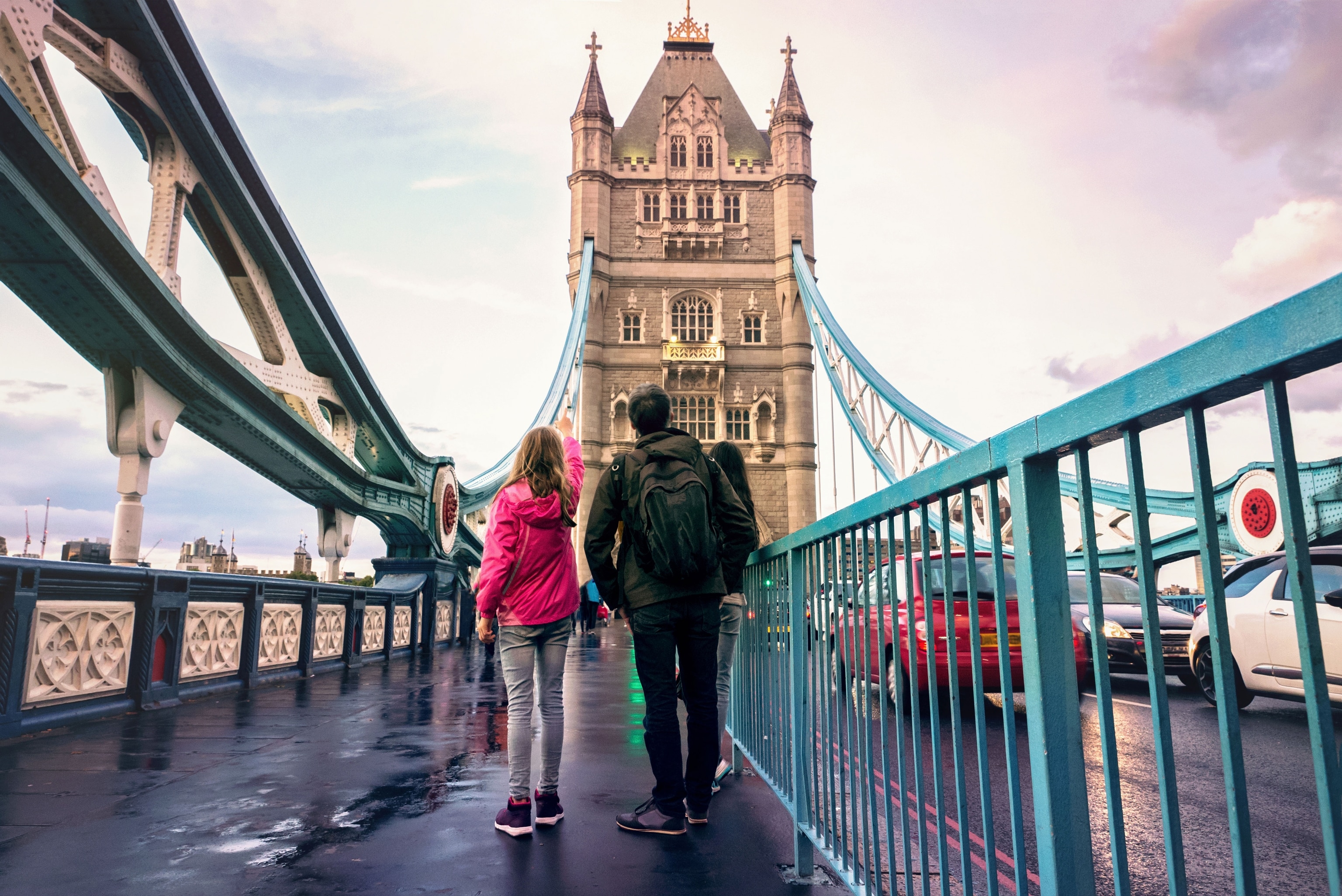 family standing just below towers on London Bridge, childing pointing up at it