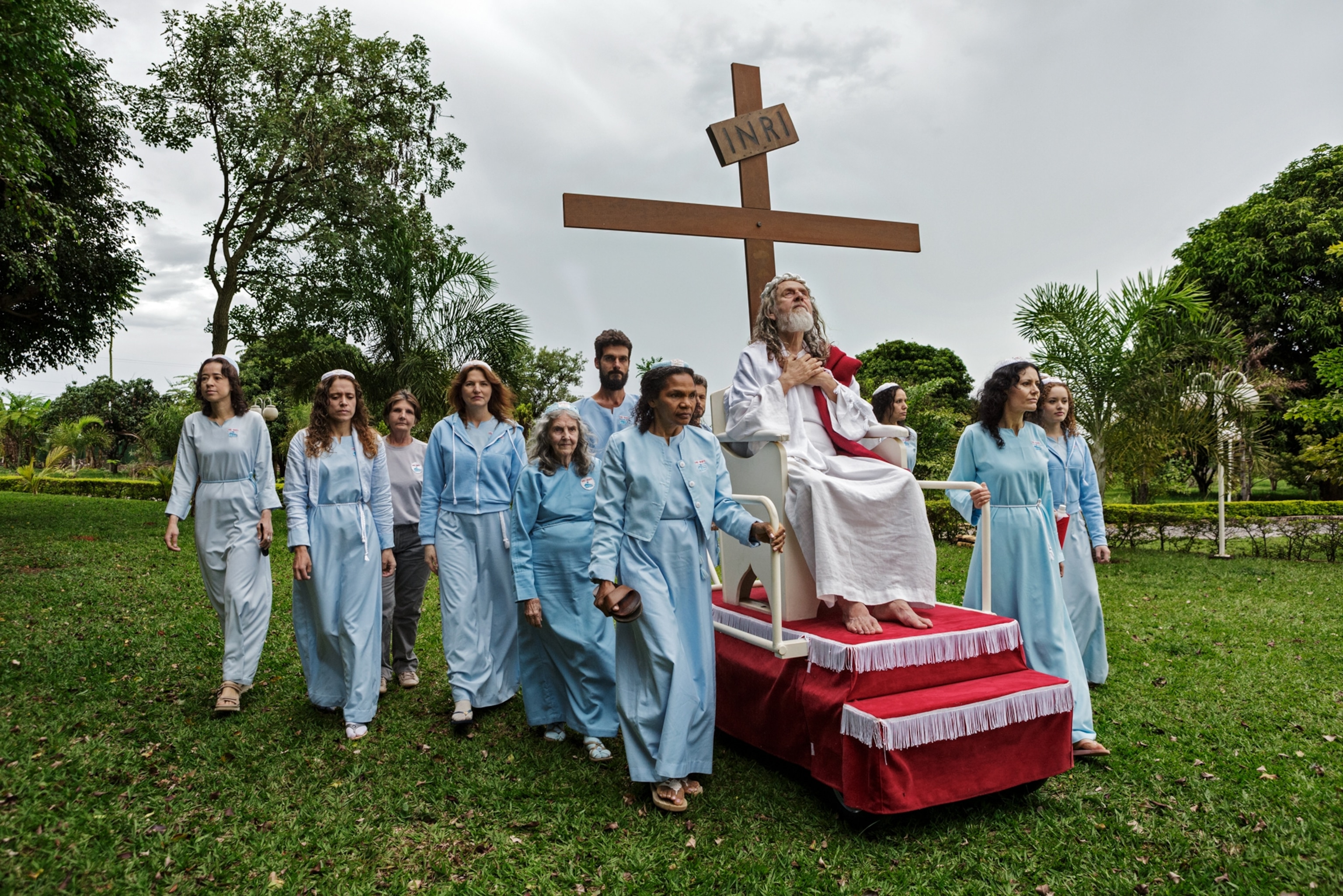 person dressed in white and being carried on a chair by women in blue dresses