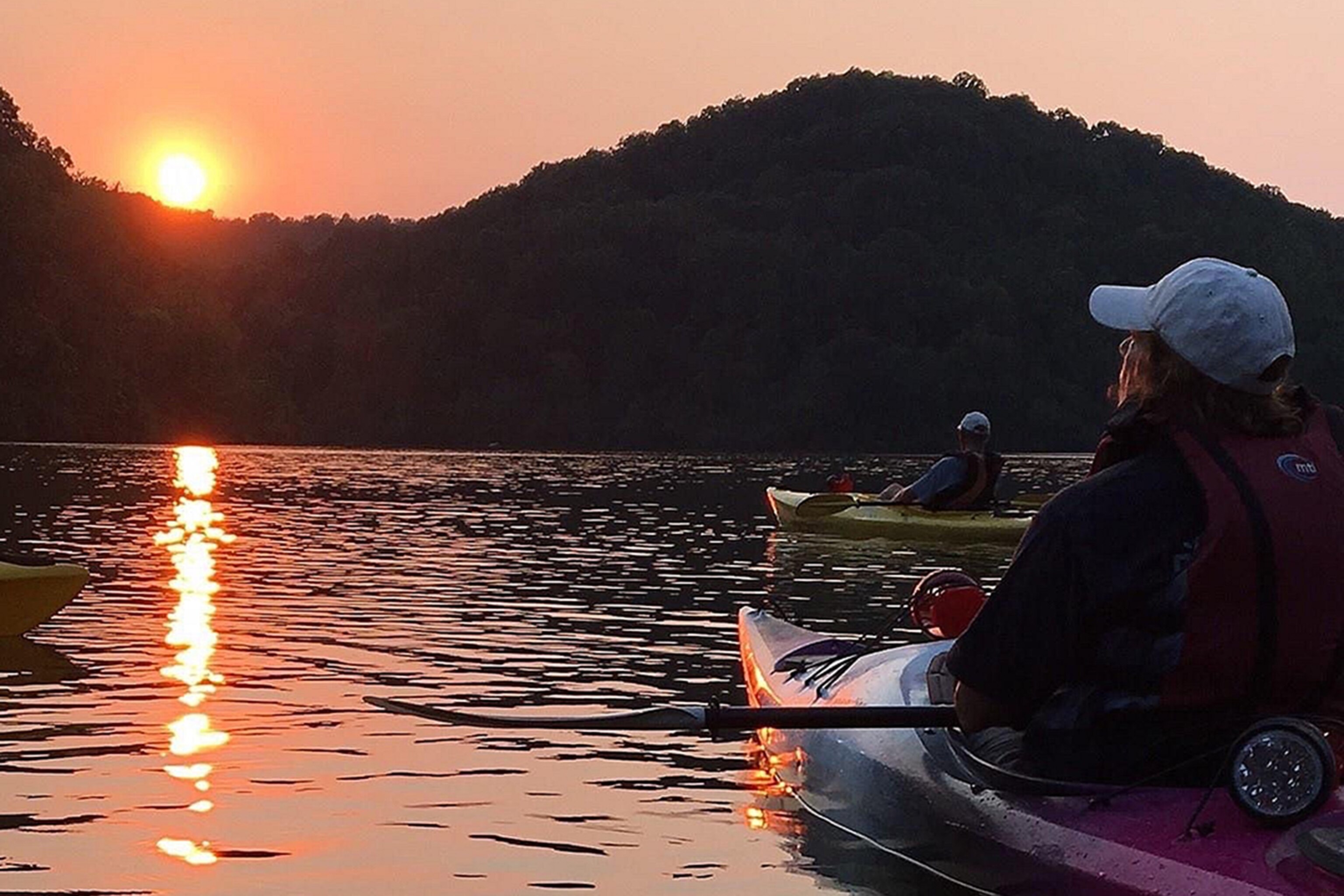 People kayaking on a lake at sunset