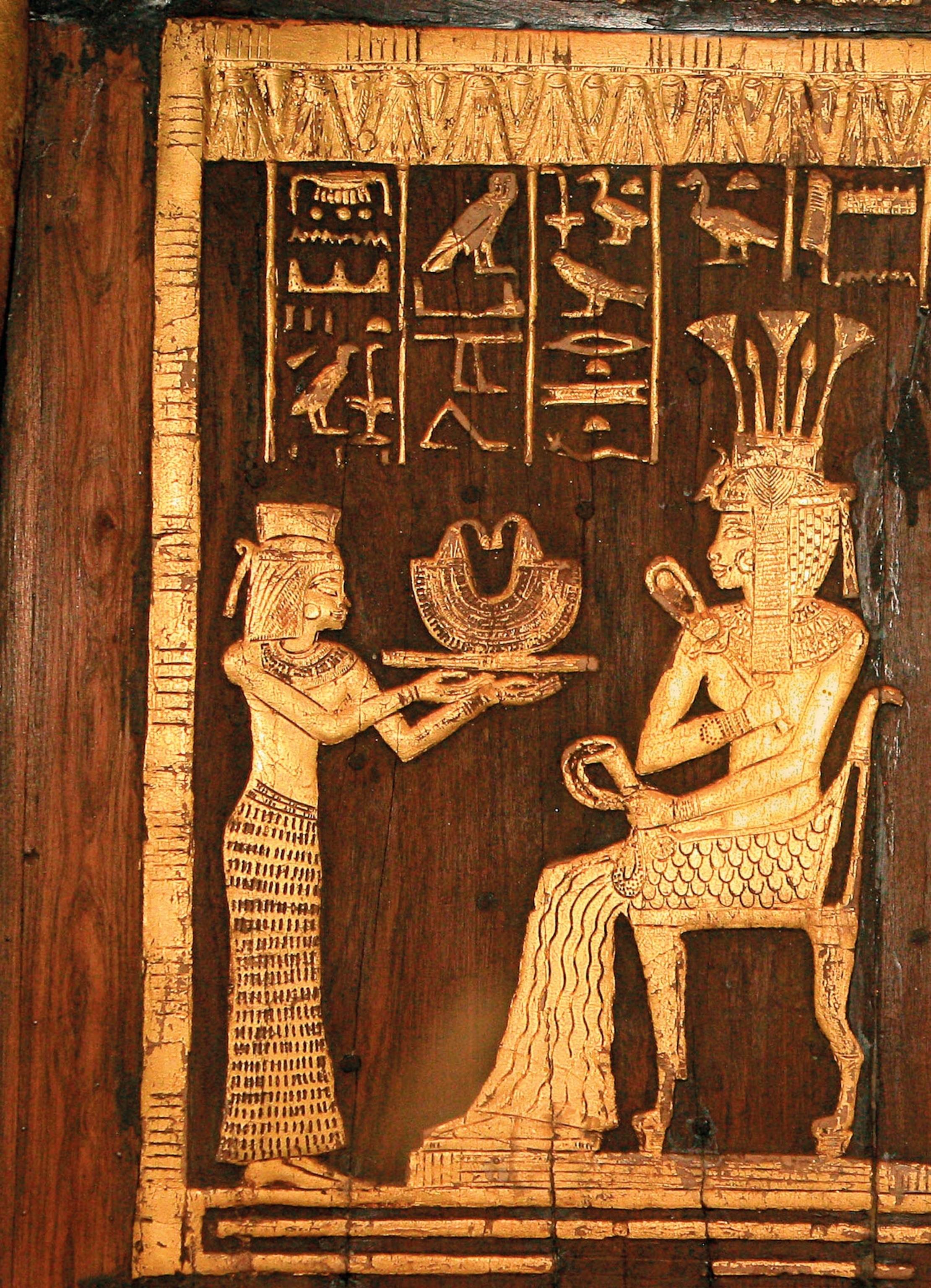 A golden relief of two people on a wooden board