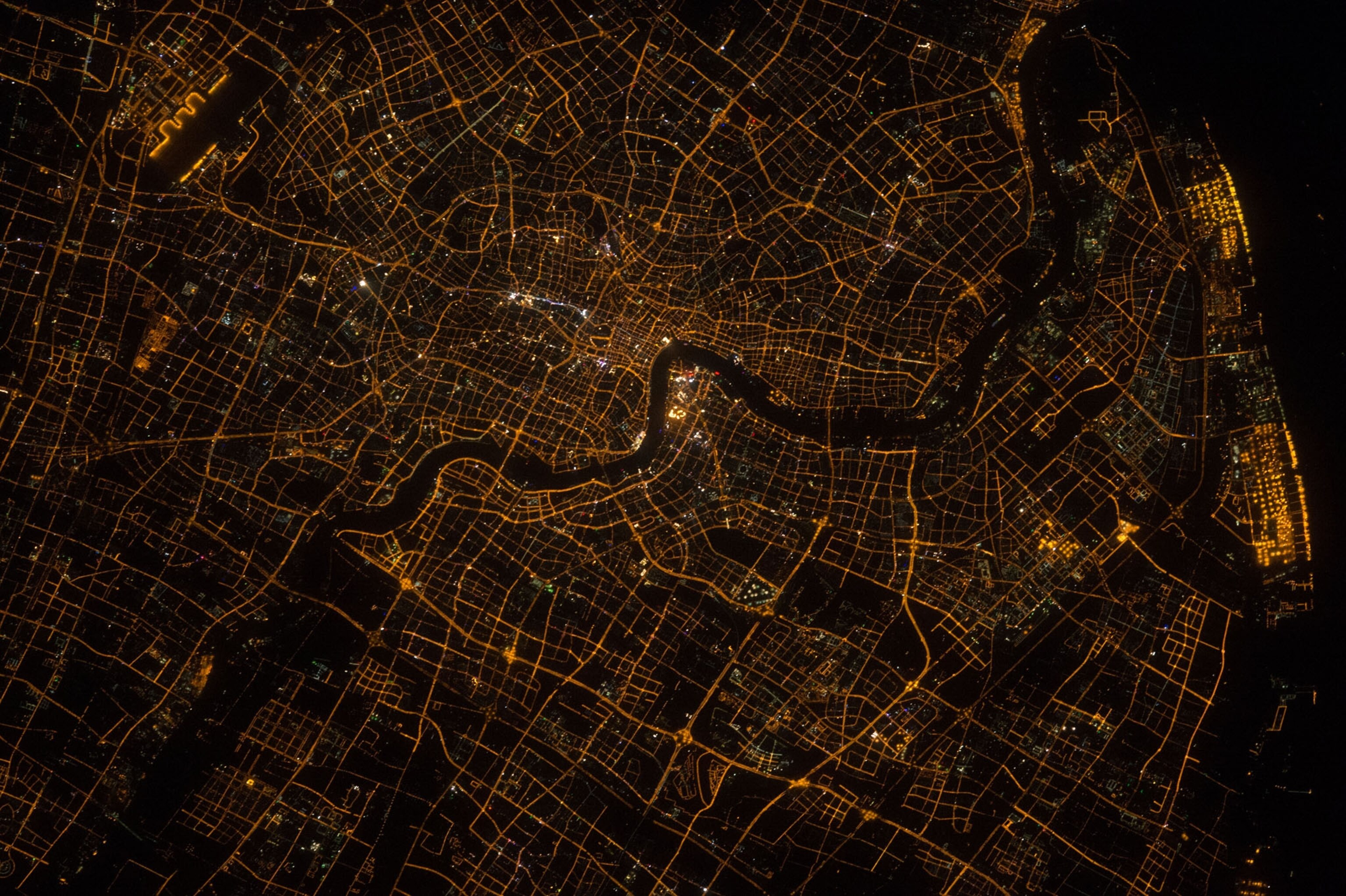 aerial view of a dense city at night with the lights highlighting the street grid