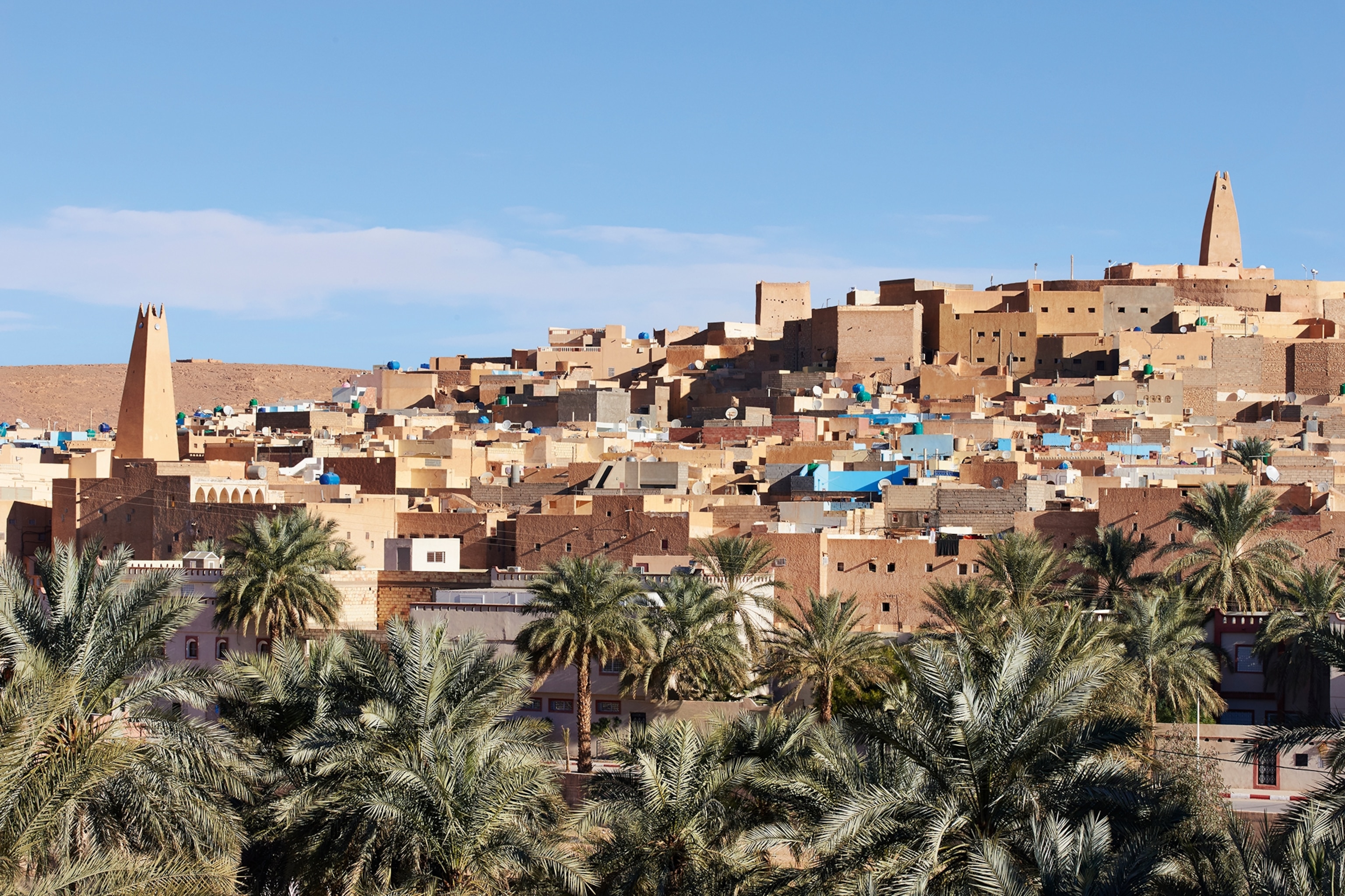 A far shot of Timimoun in Algeria. The builds are warm shades of red and copper, with occasional blue walls painted throughout.