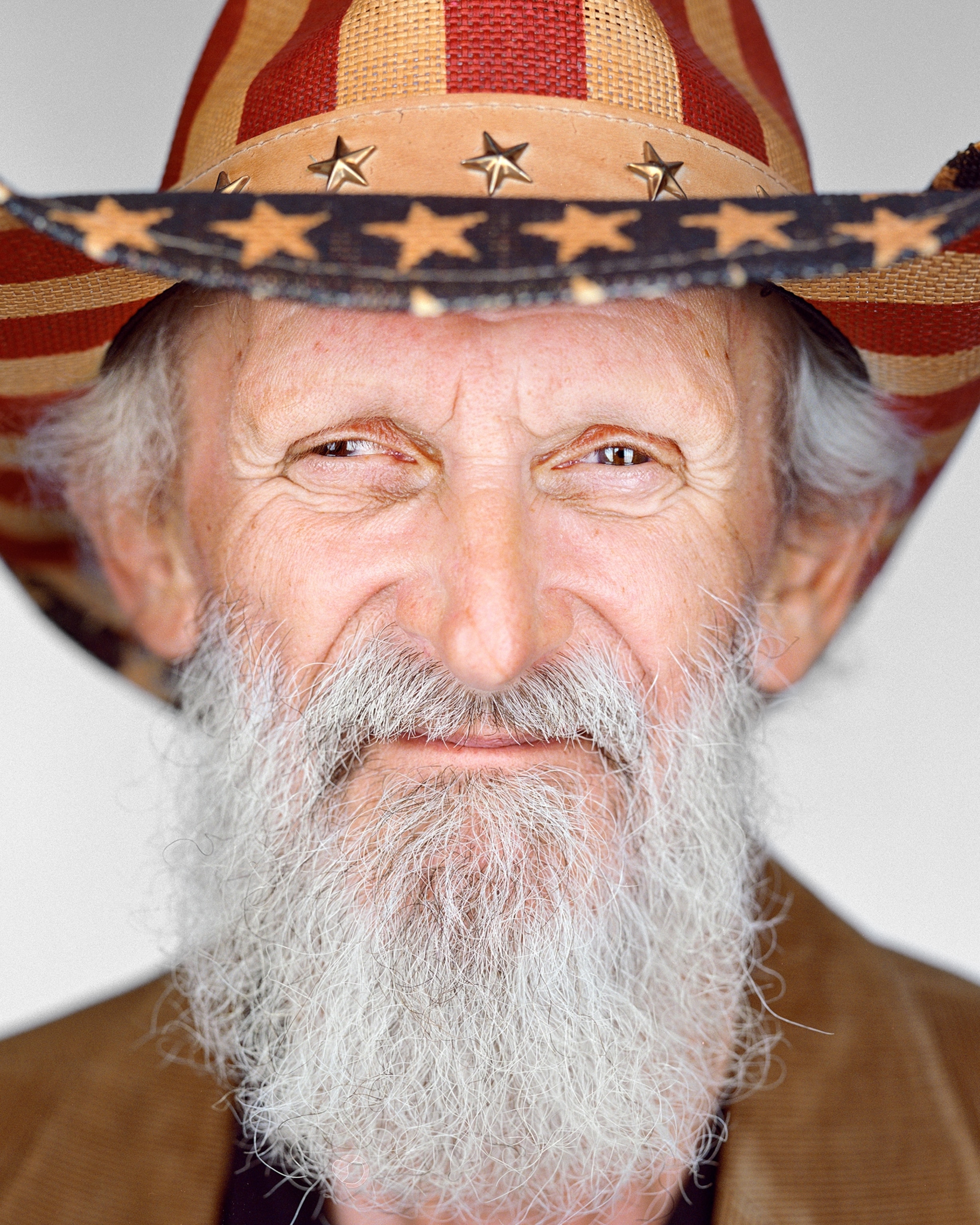 a man with grey beard wearing American Flag hat.