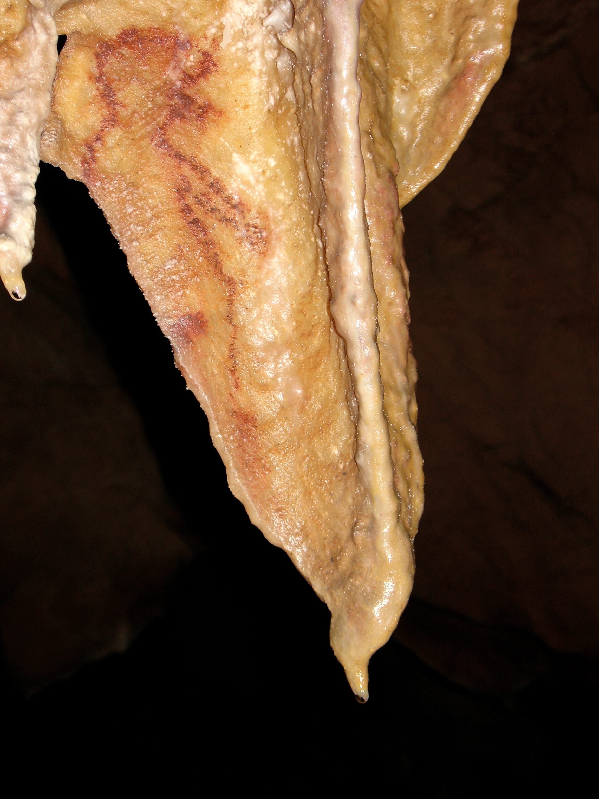 A red female figure is on a stalactite in the Tito Busillo Cave.