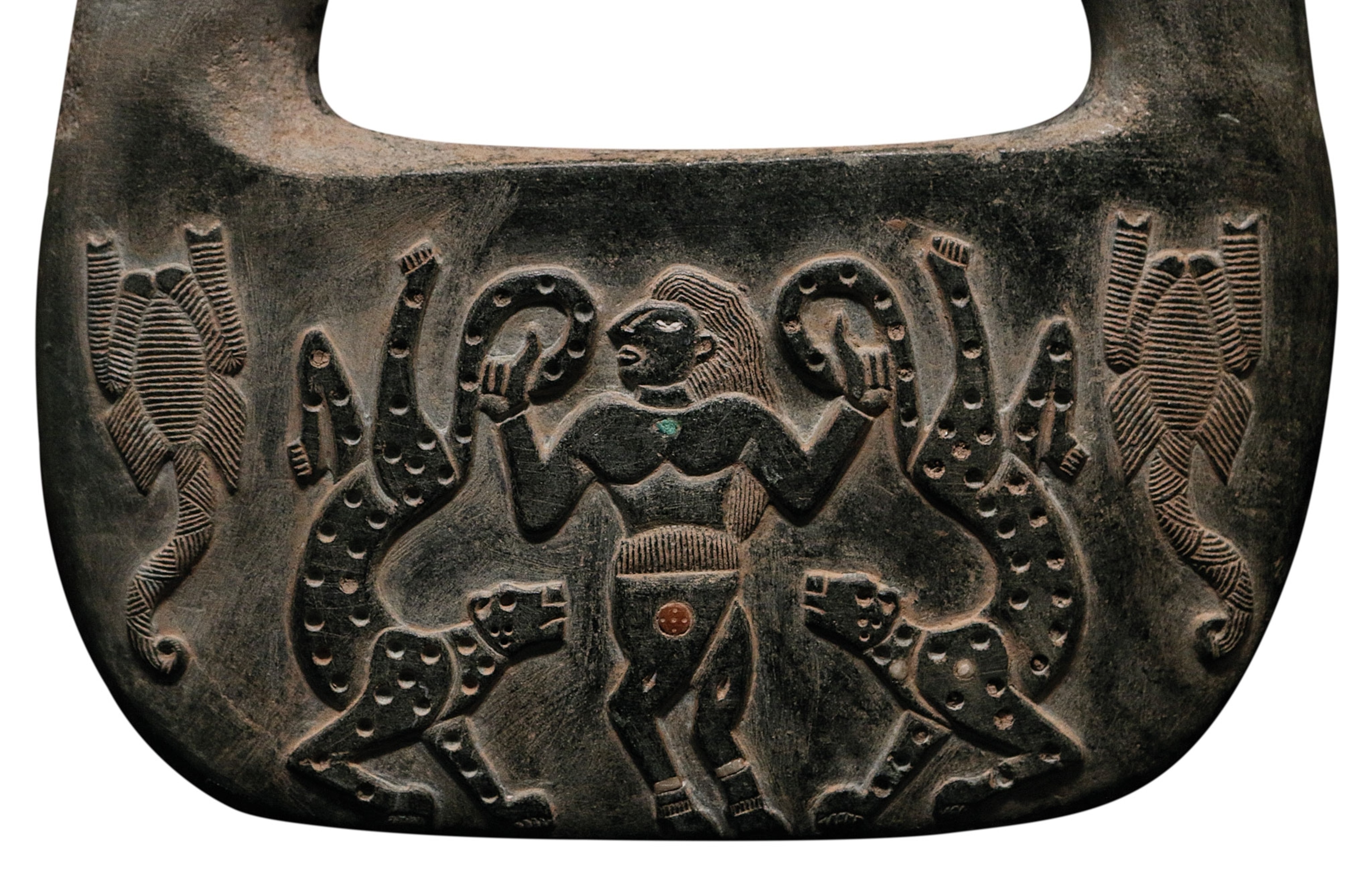 A stone relief of a man holding two cheetahs by the tail