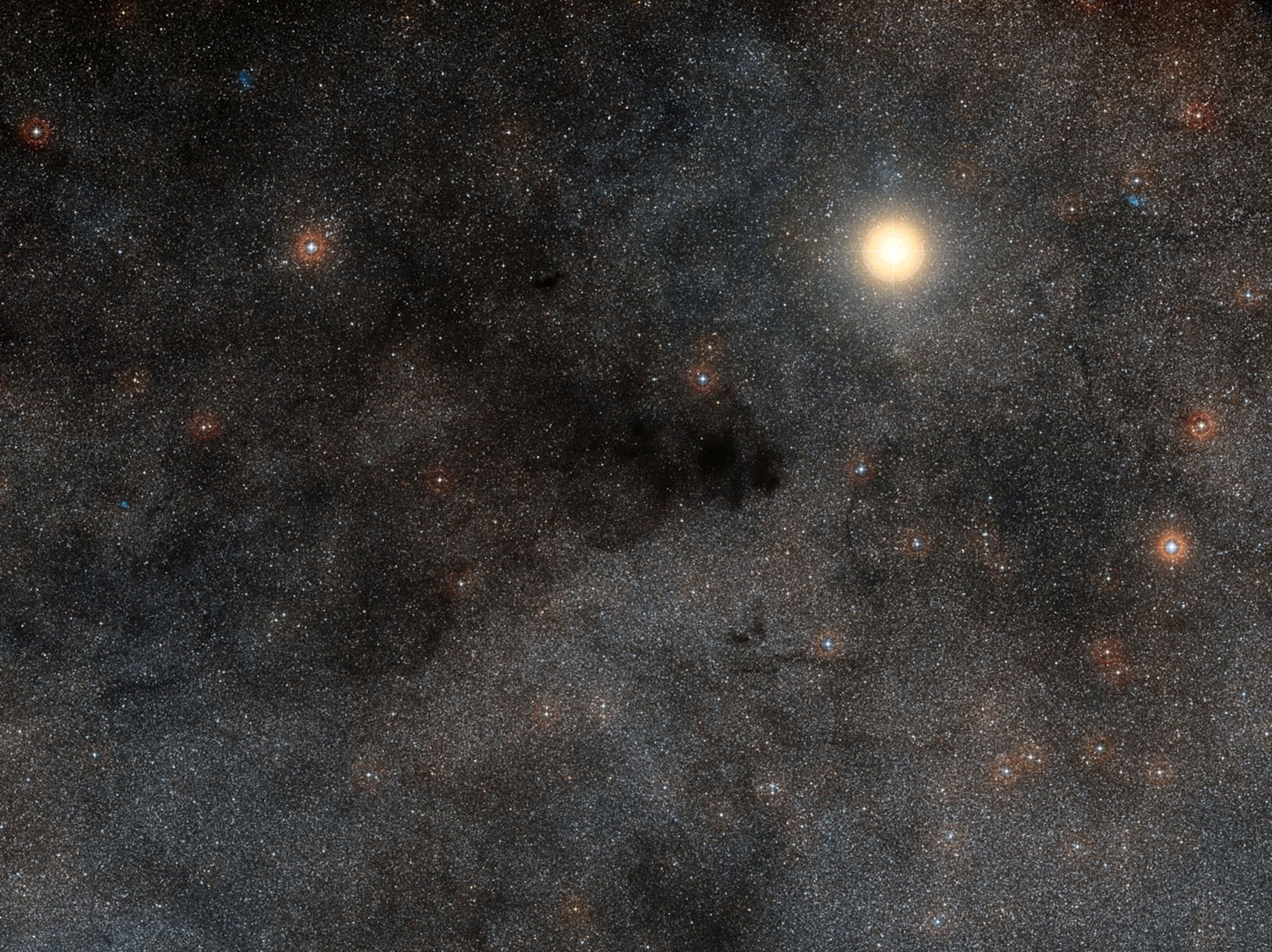 This rich landscape is part of the small constellation of Crux (The Southern Cross). The very bright star is Alpha Crucis, also know as Acrux, one of the four stars that make up the famous cross shape. Most of the upper left part of this image is filled with dark dusty clouds that form part of the huge dark nebula called the Coalsack. (Image and caption: ESO)