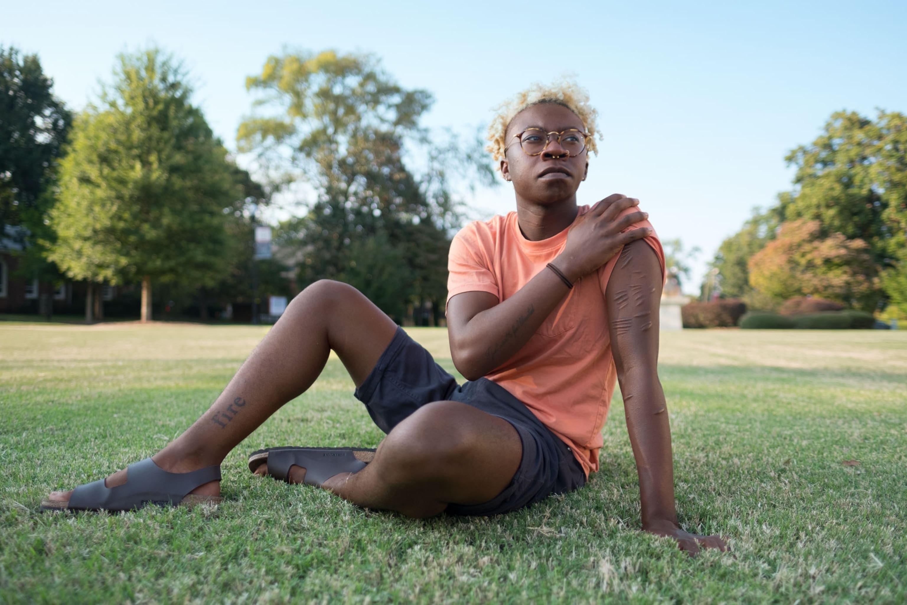 a young black student sitting on a lawn outside for a portrait