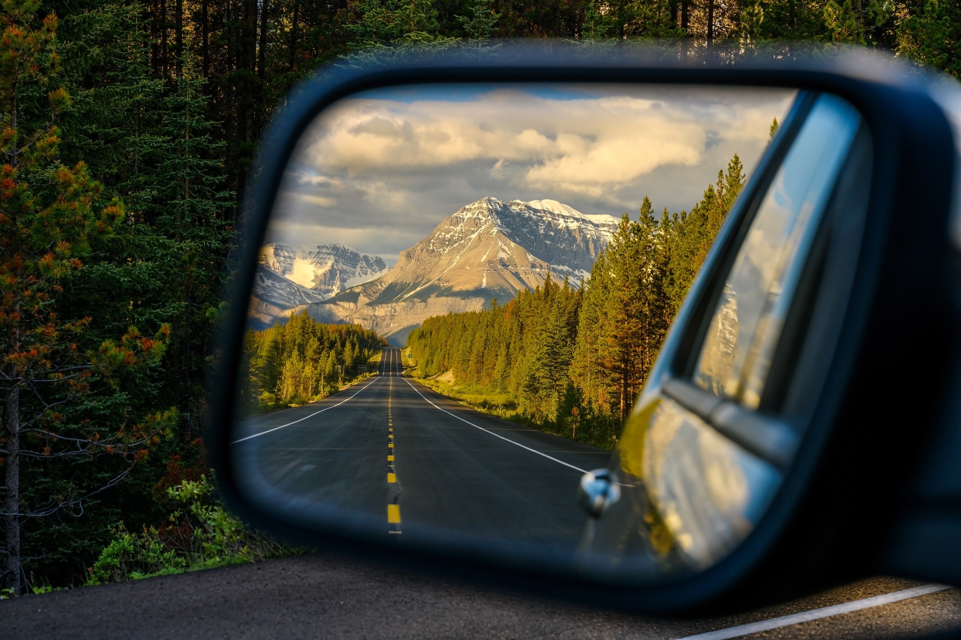 car wing mirror view of a mountain