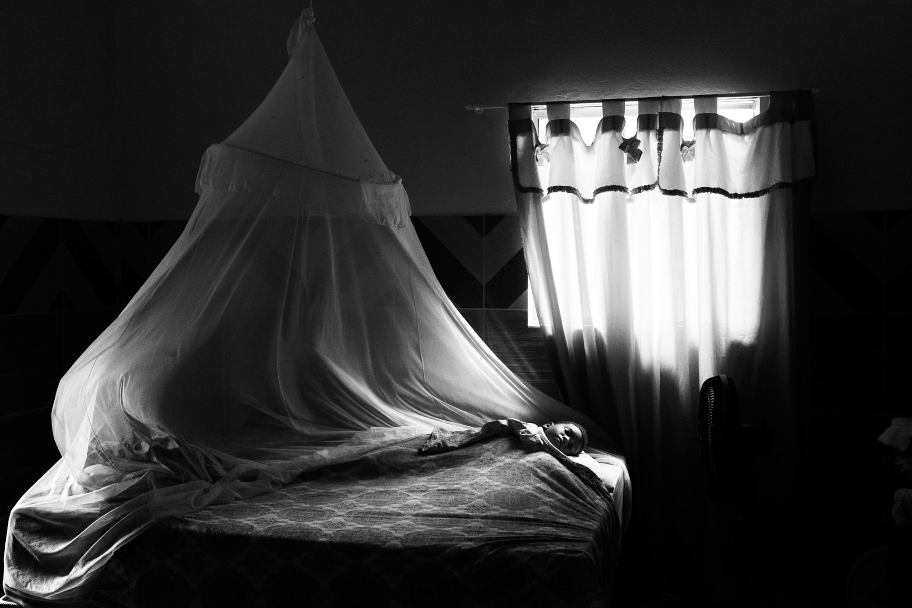 A young boy named Enzo Pires sleeps in his grandmother's bed.