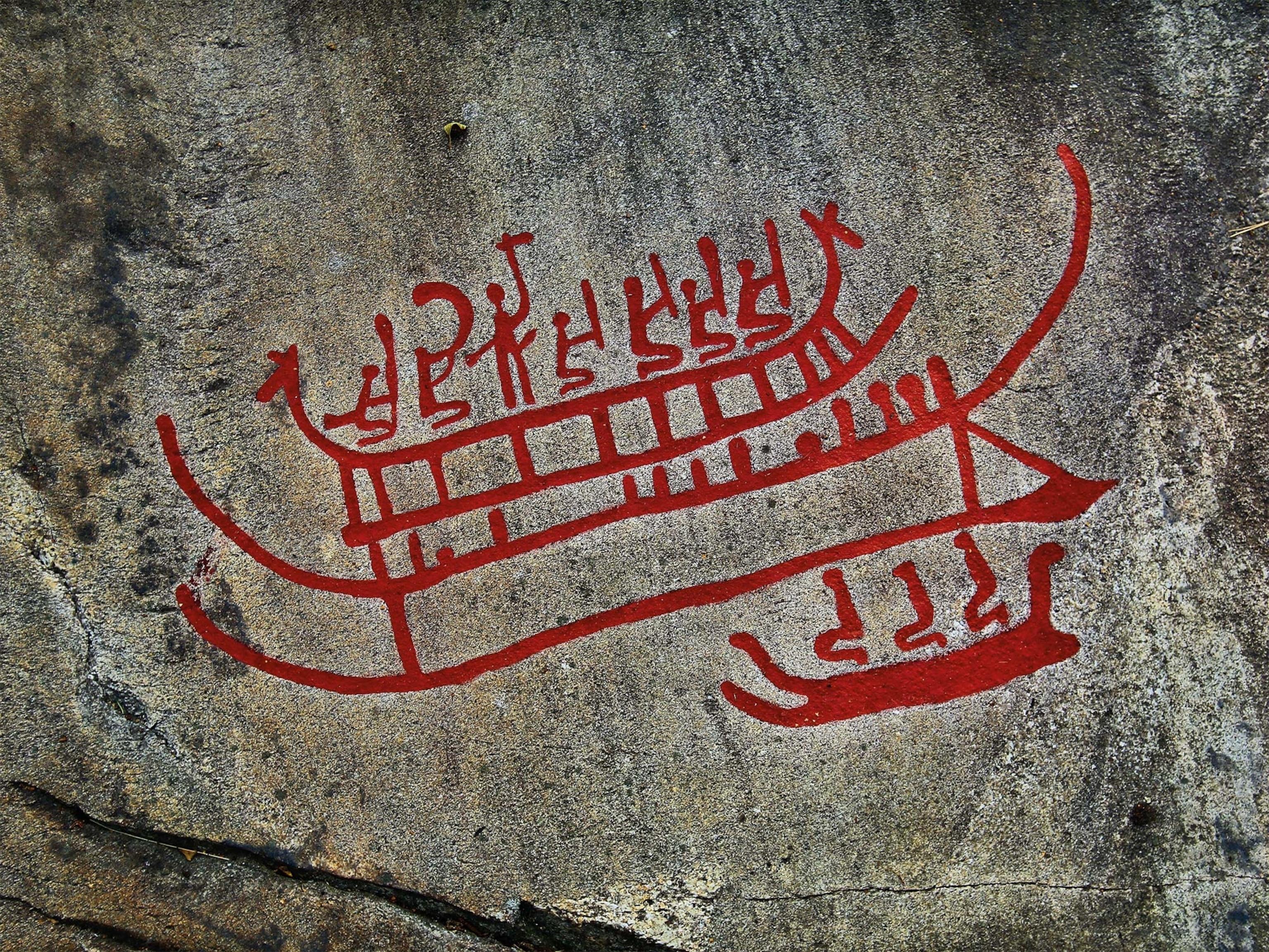 A red petroglyph showing boats and a crew