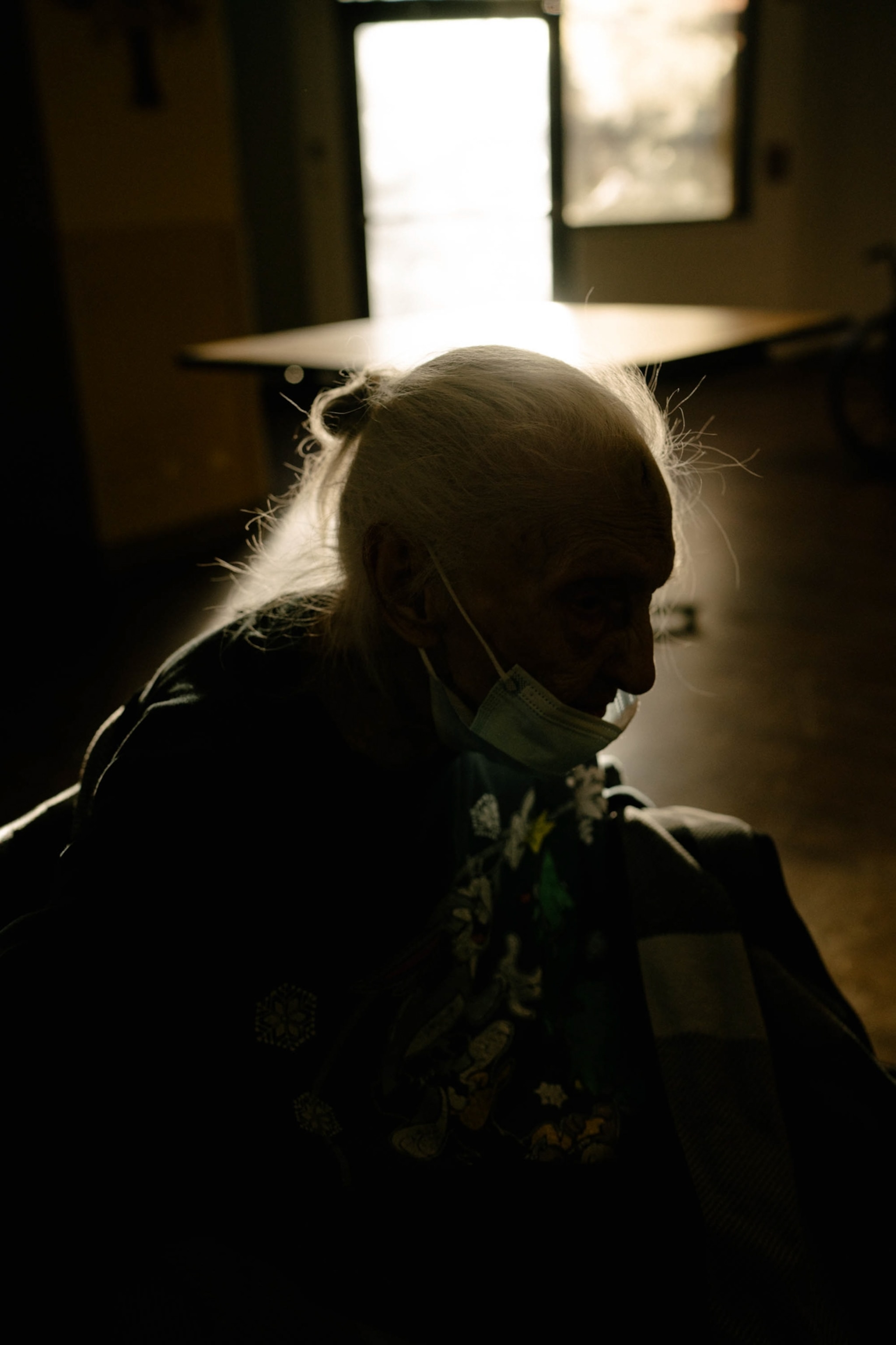 Mary, who has late stage Alzheimer's, is seen silhouetted as she moves her wheelchair through her memory care unit.