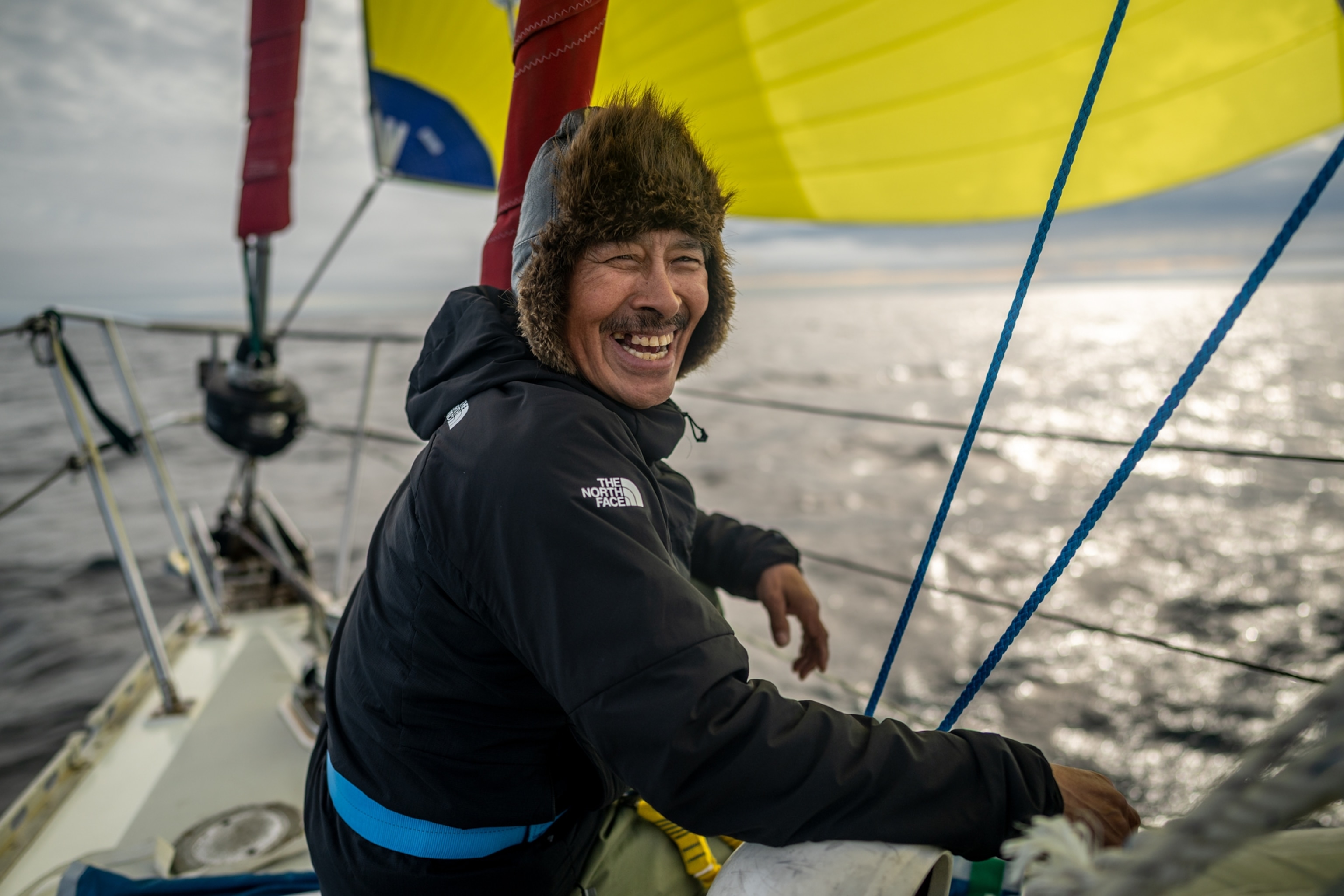 Man smiling into camera while working on the foredeck.