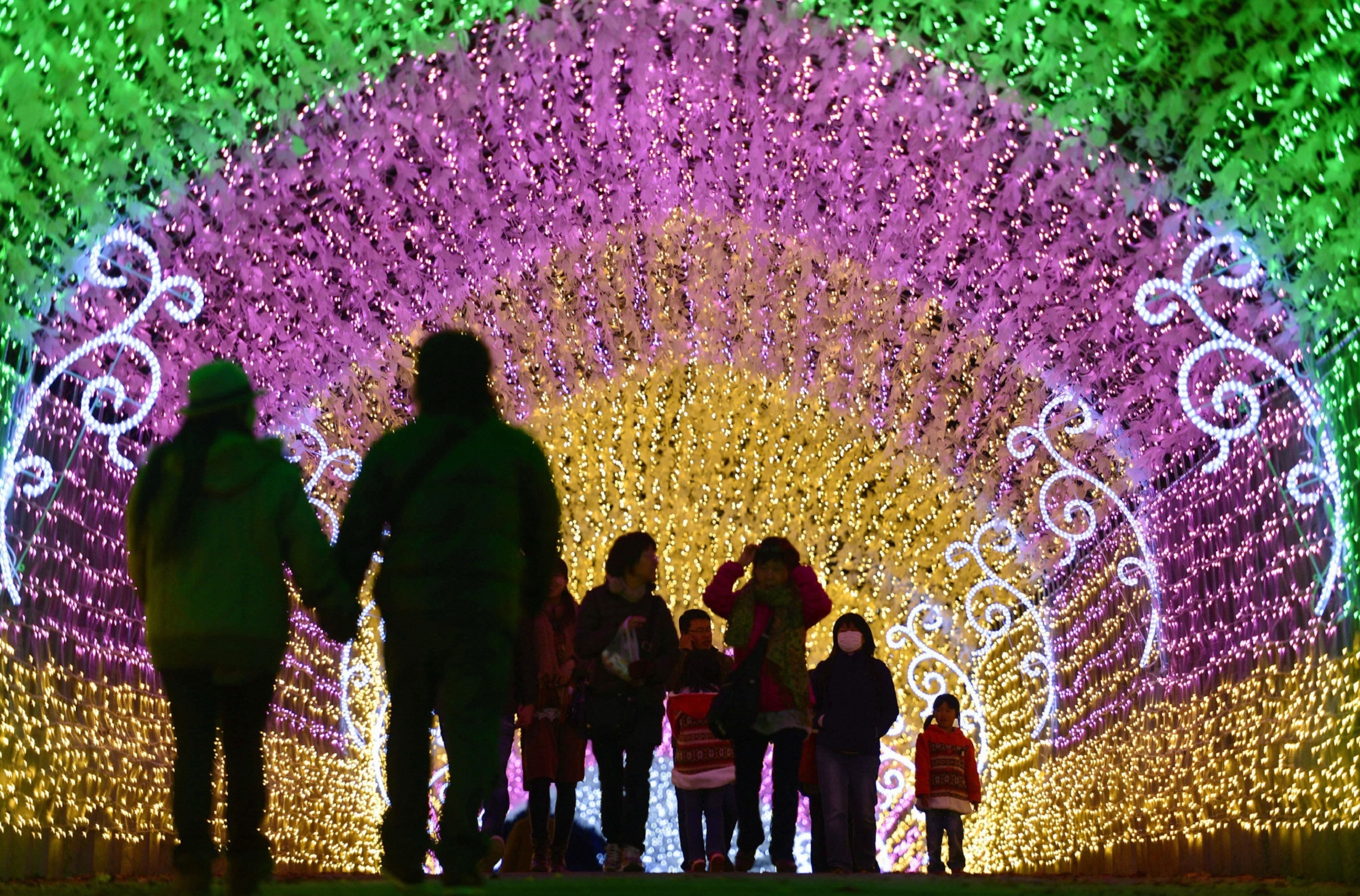 People walk under a tunnel of lights