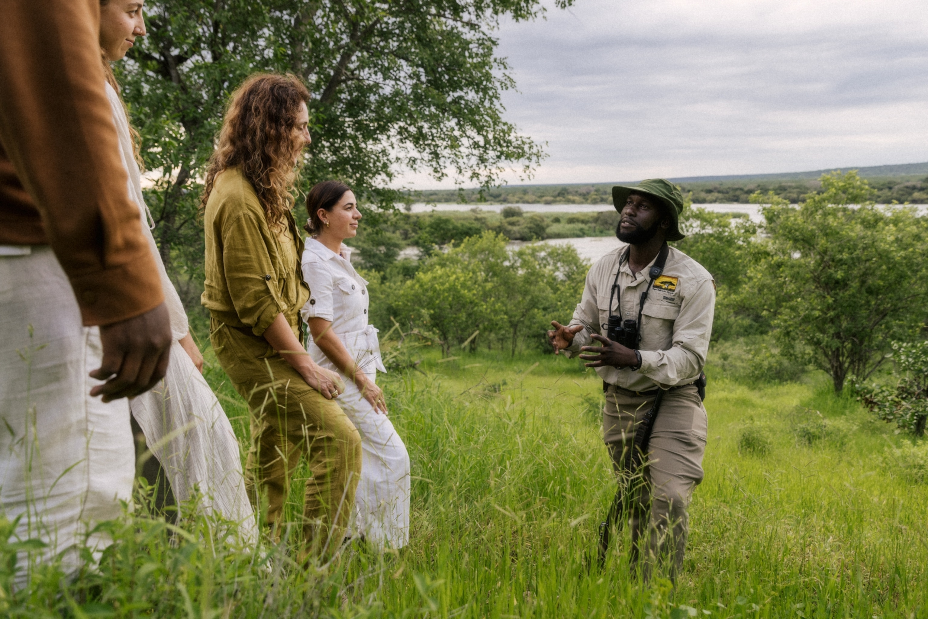 People listen intently as a man speaks outside in the brush.