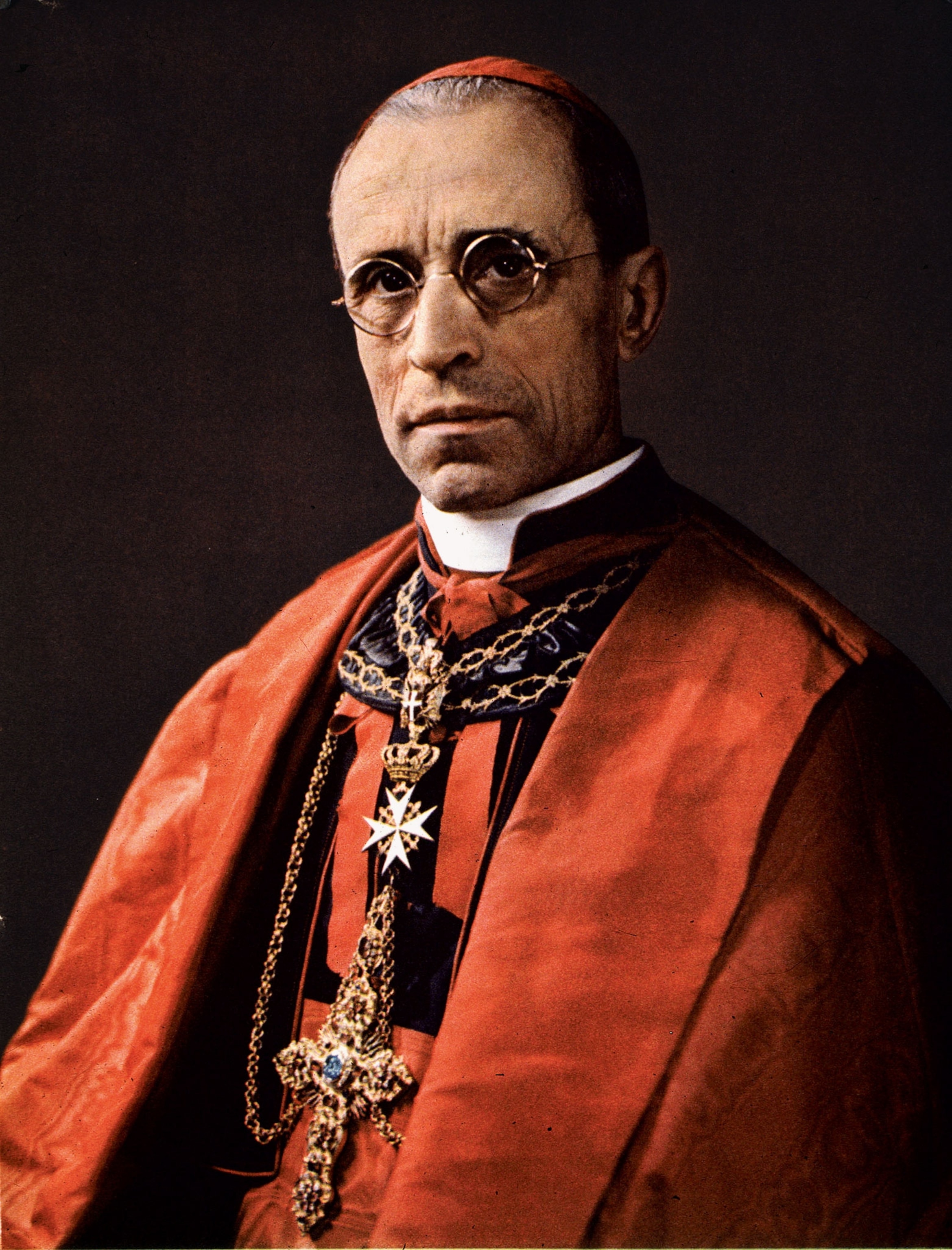 A photograph of Pope Pius XII sitting in red papal wear