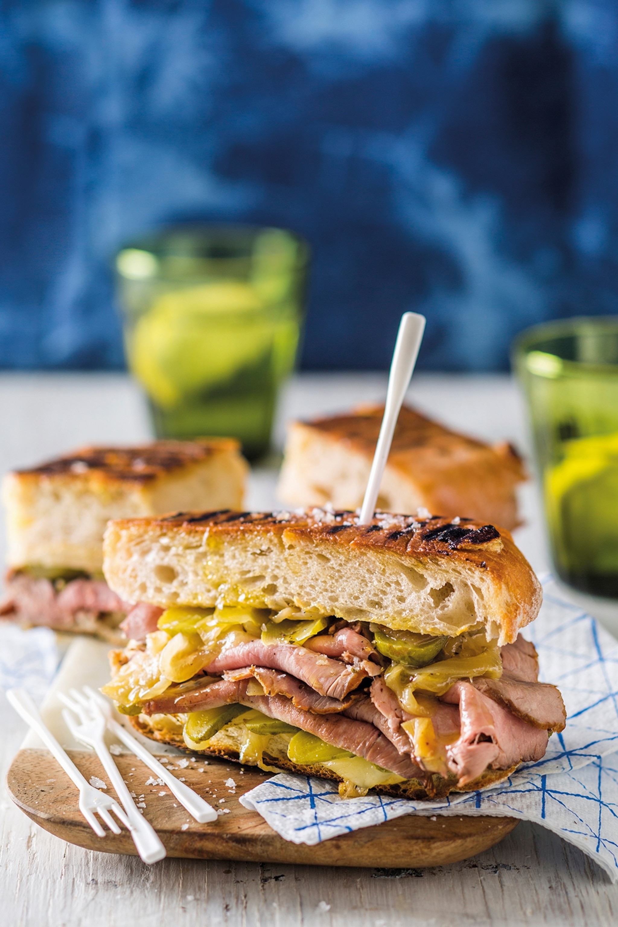 One half of a grilled sandwich with smoked ham, pickles and cheese secured by a plastic pick.