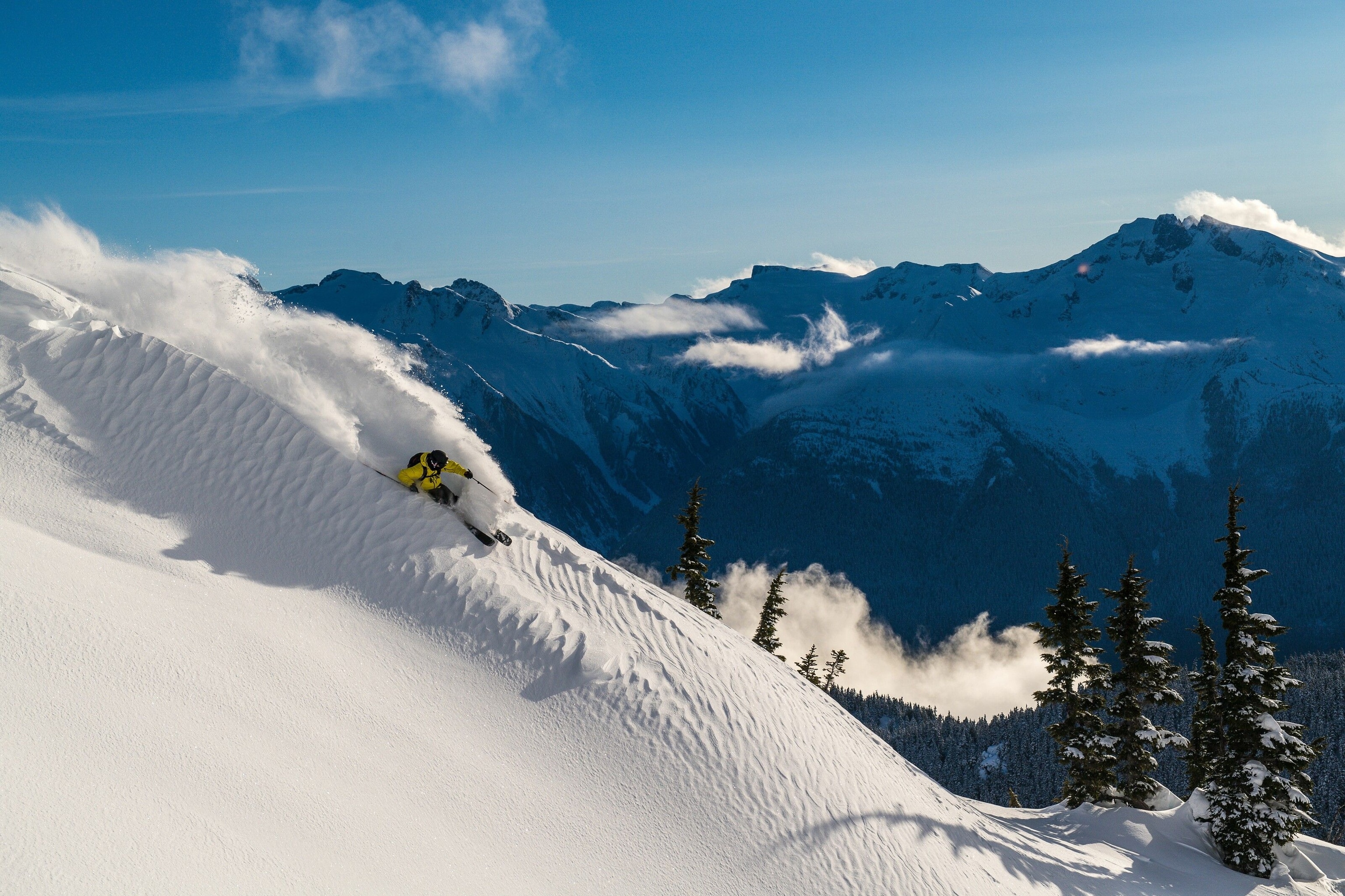 A skier flies down a powder ridge on an untracked Bella Coola slope.