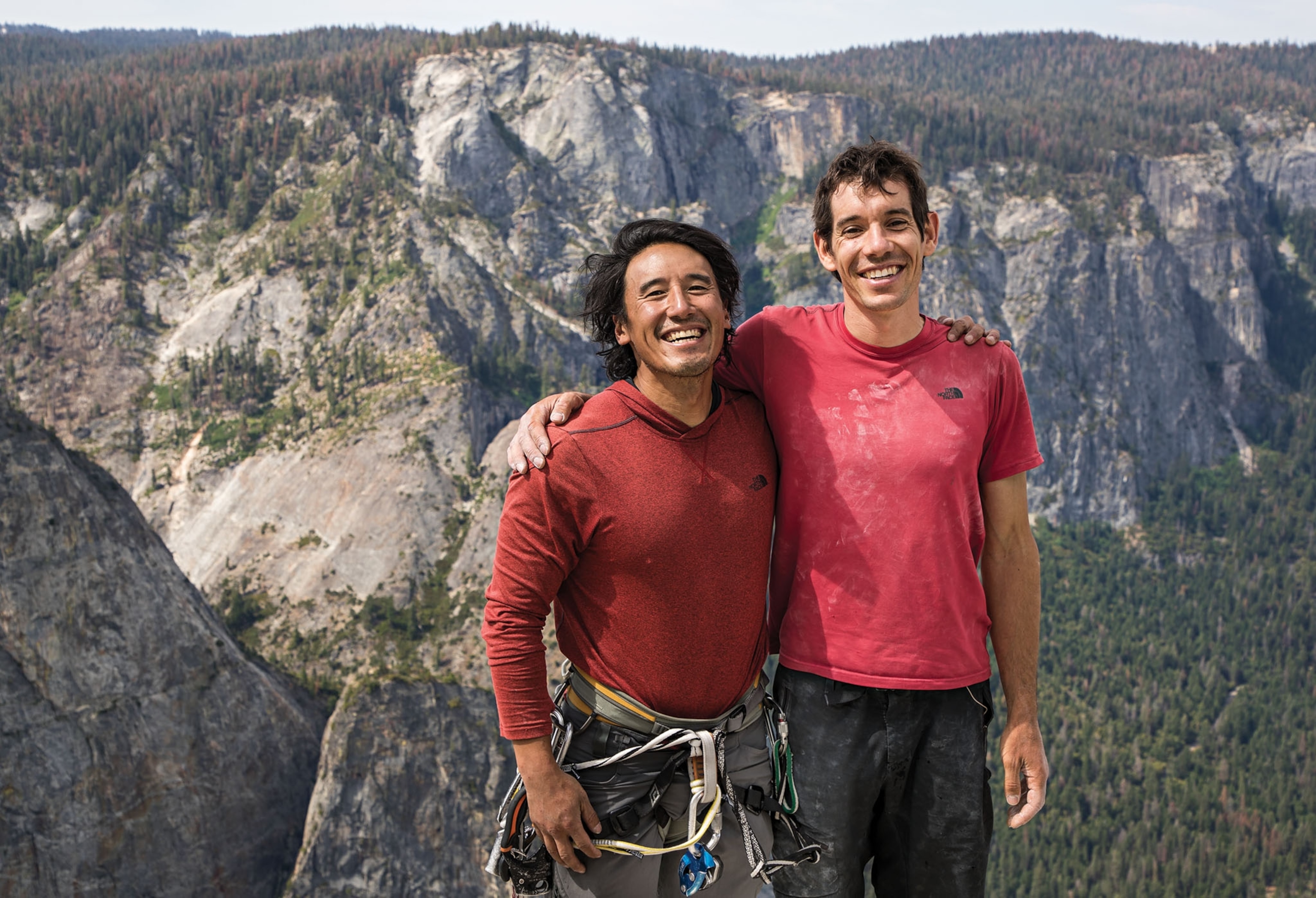 two men with their arms around each other on top of a mountain