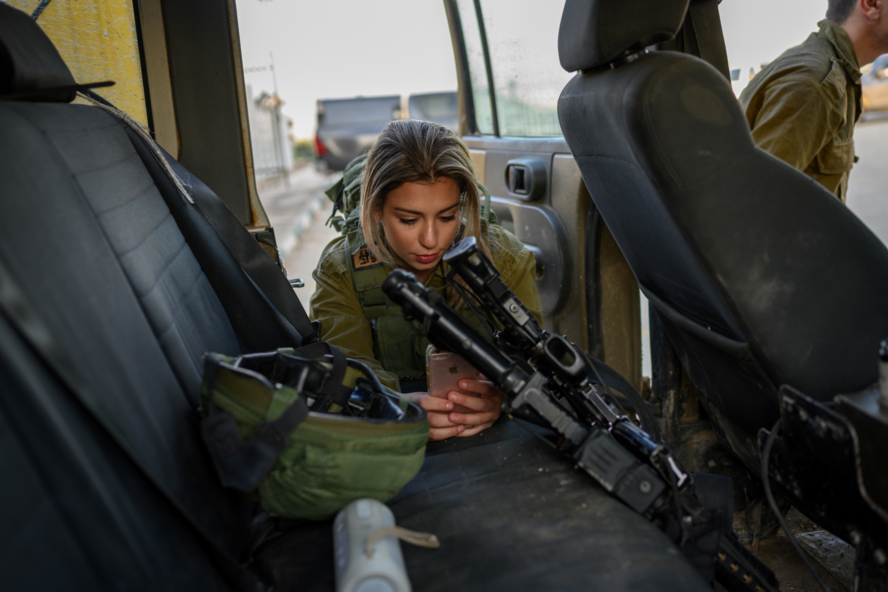 a woman in the back of a van holding her gun and cell phone