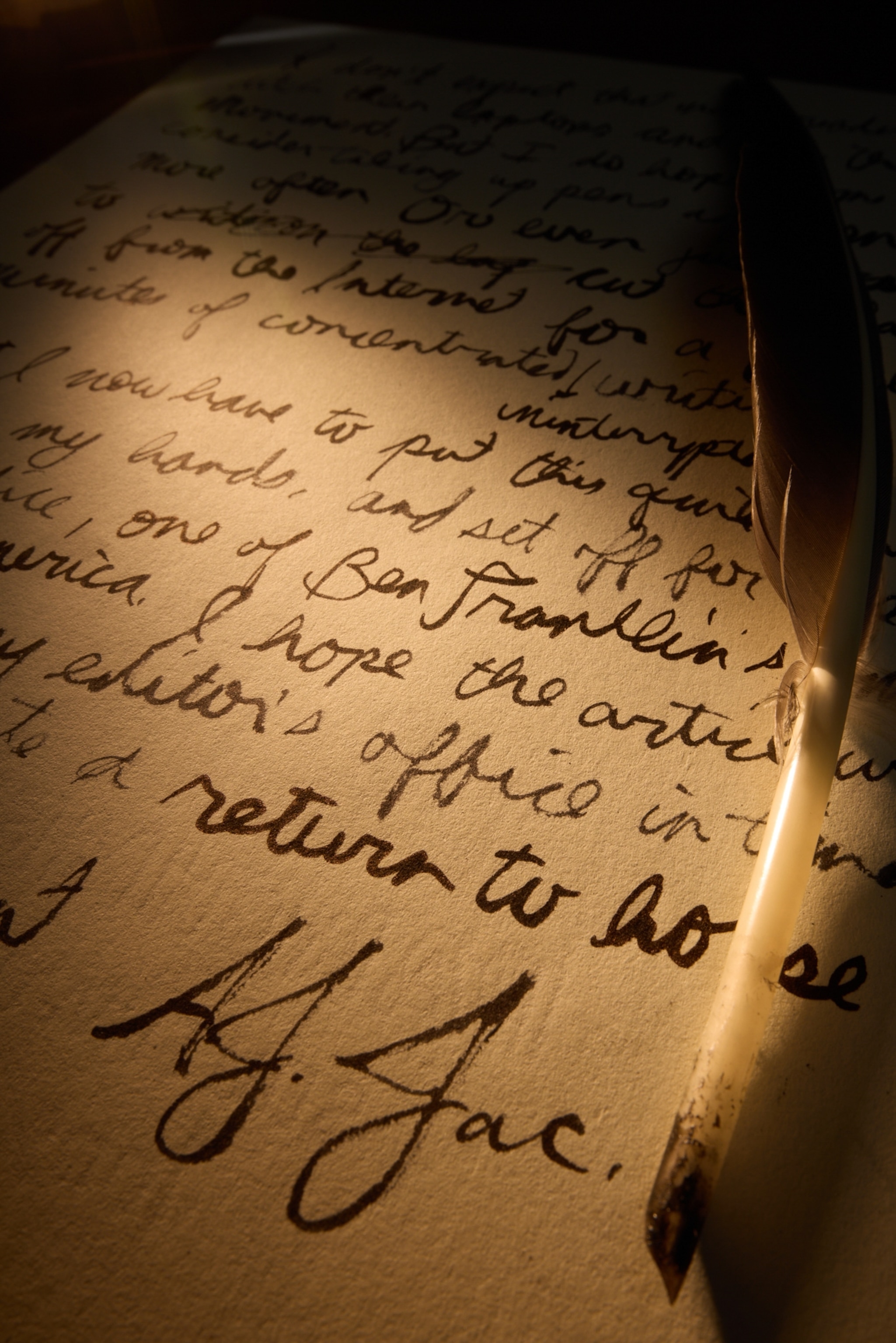 A piece of paper with Calligraphy on it and a pointy good feather pen.