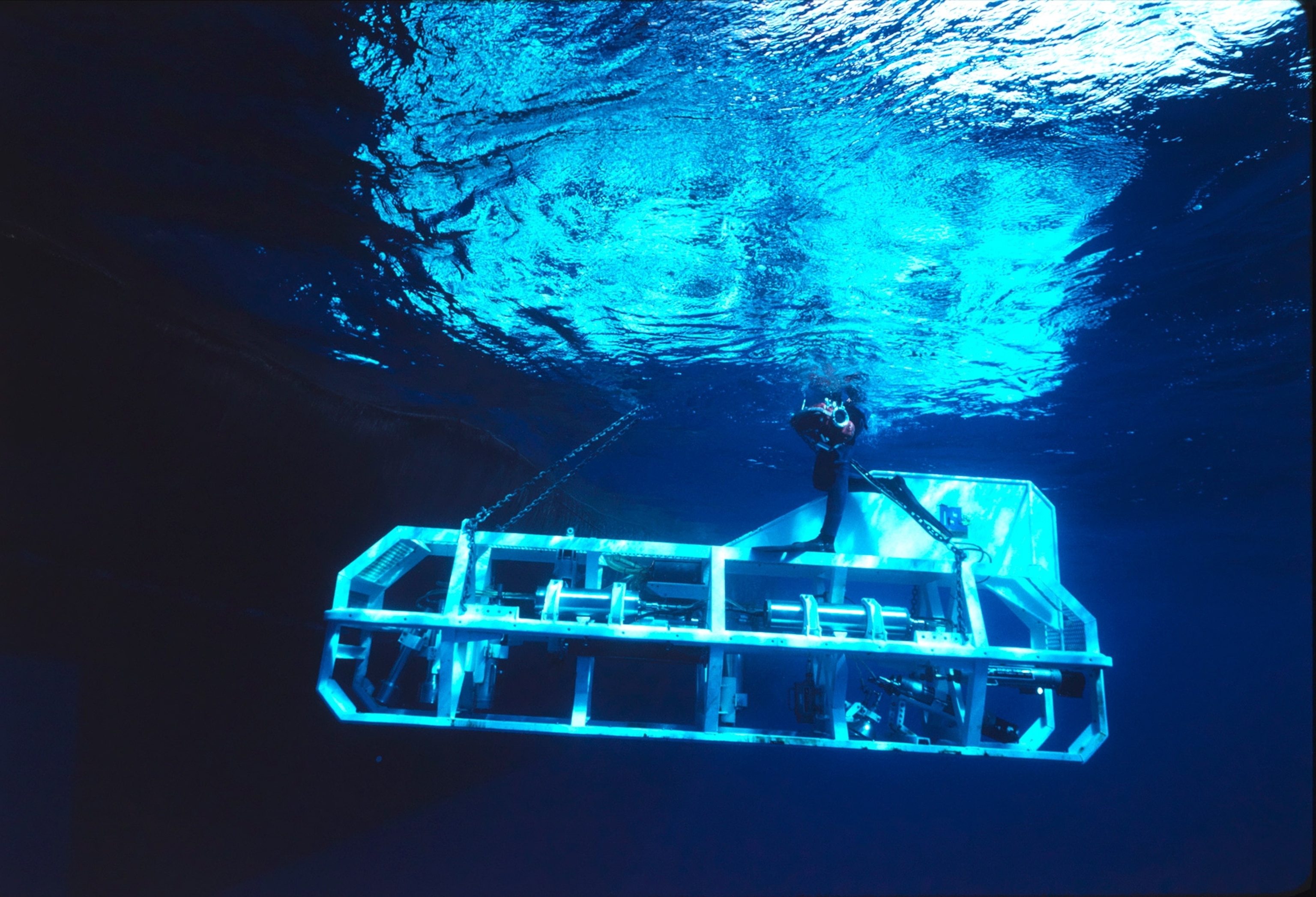 Blue waters illuminate the frame of a ship going under.