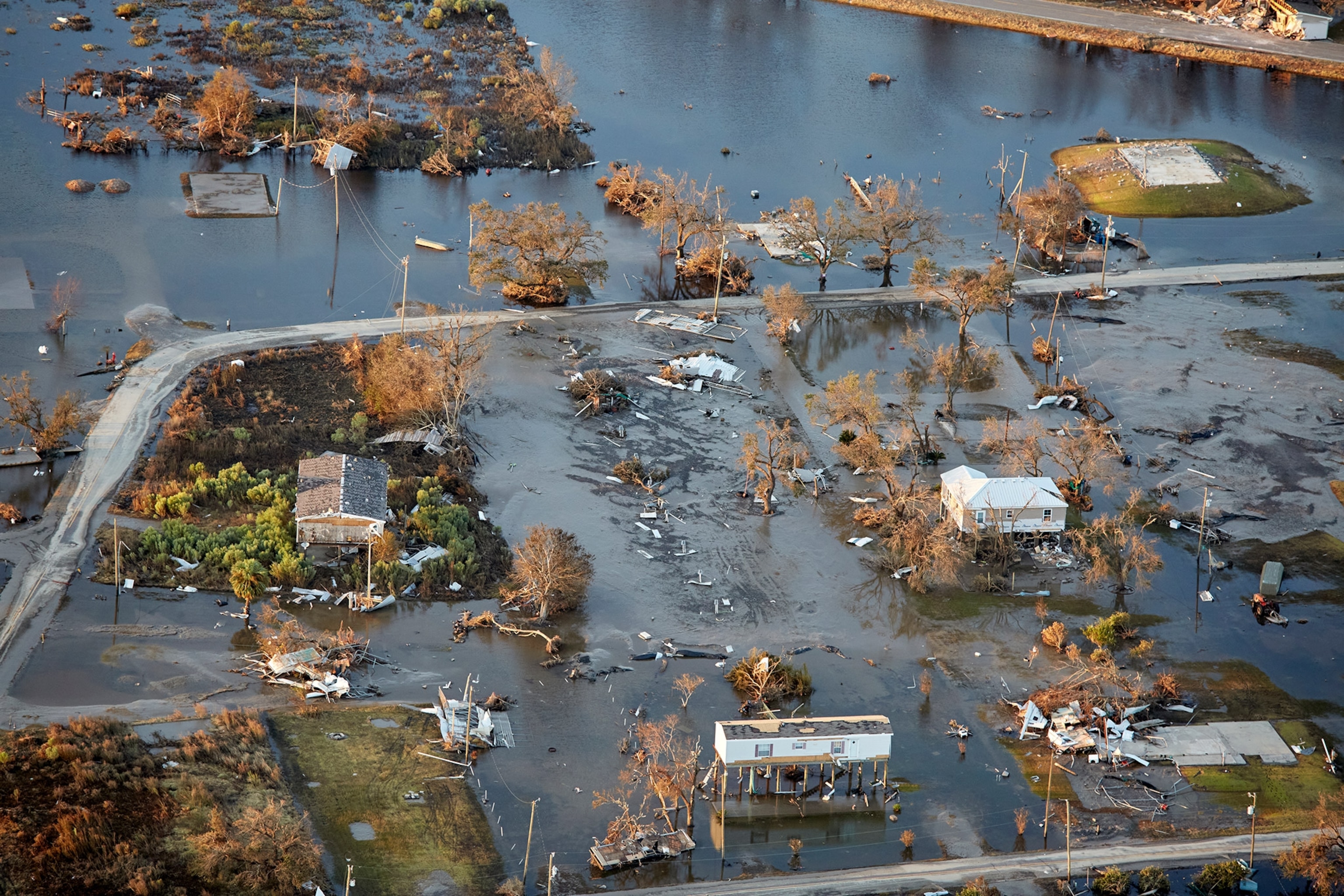 A town sits destroyed, the sides of housing are completely gone while others have either toppled over or have been swept away leaving only the foundation.