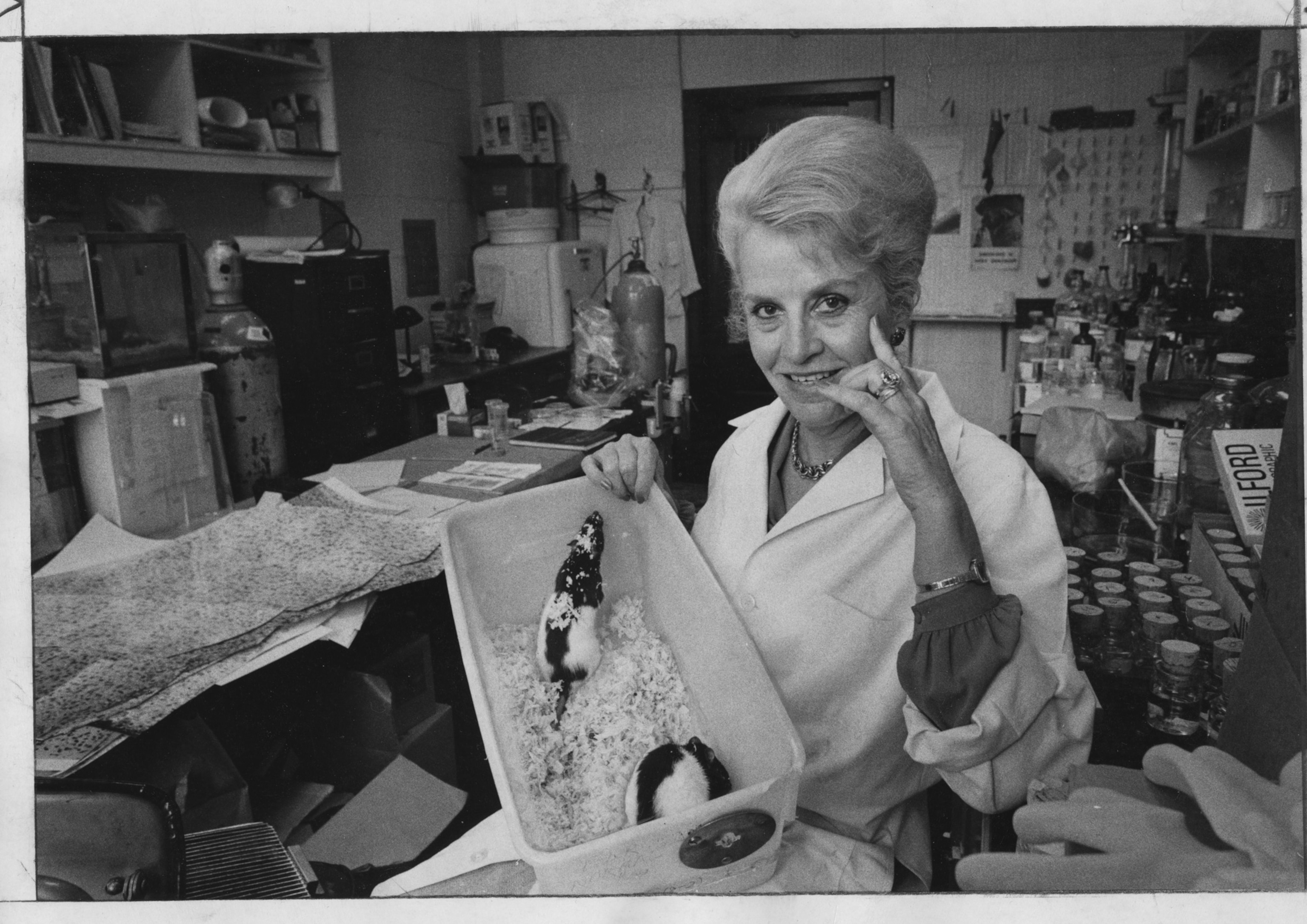 Photo of woman in white lab coat holding box with two mice