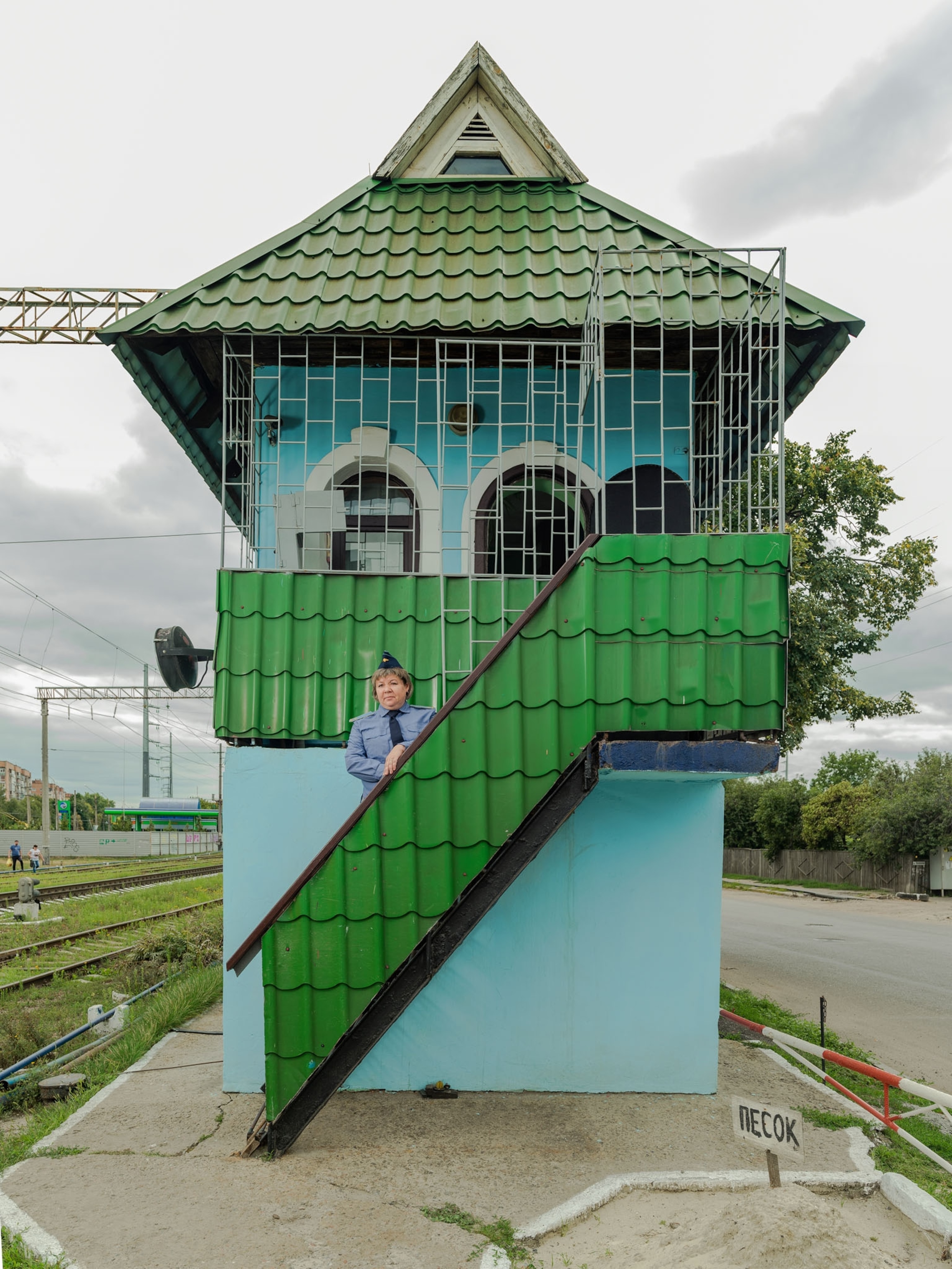 woman in uniform standing on stairs of green and blue house.