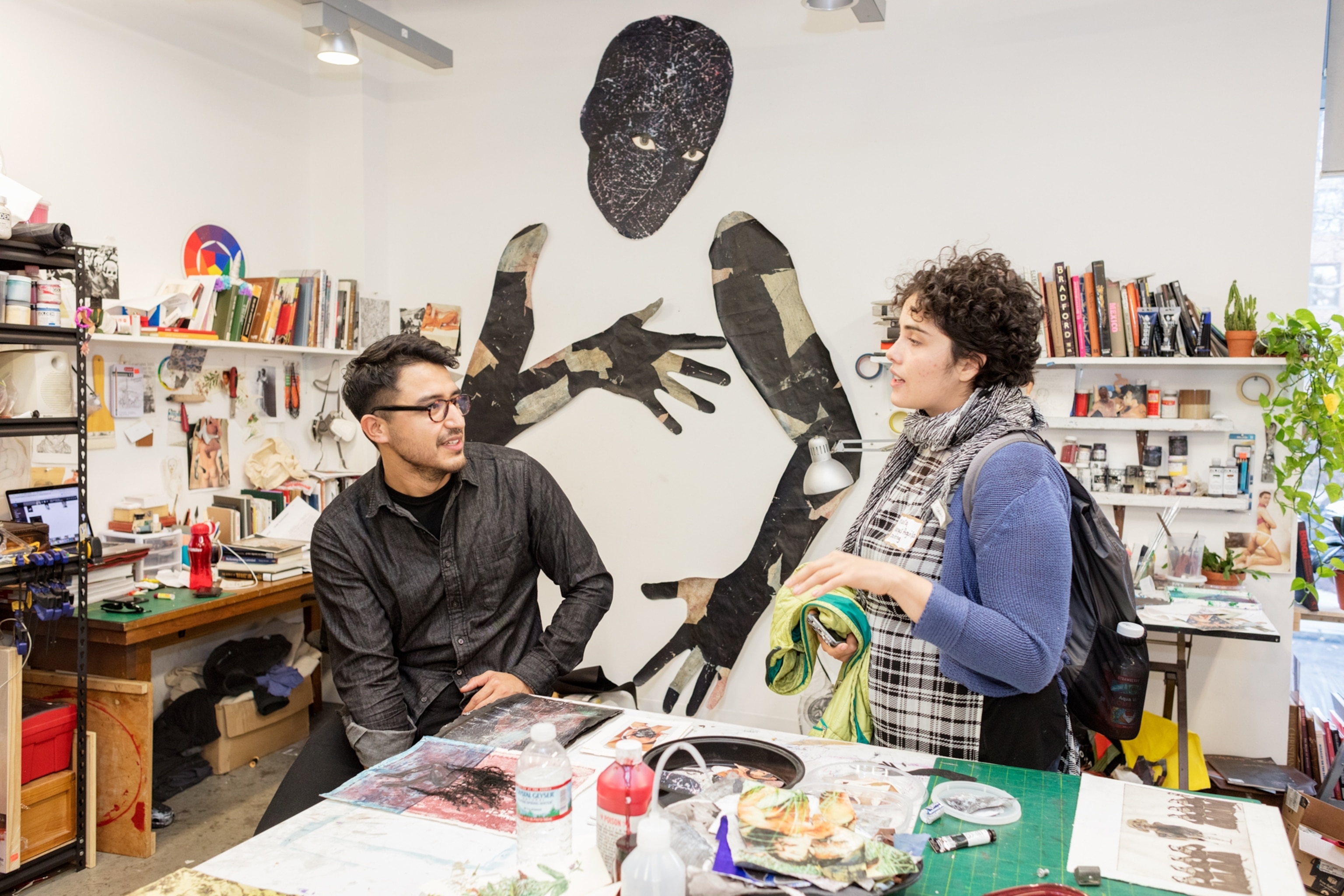 a student in his studio talking to a prospective student with a human-like figure above
